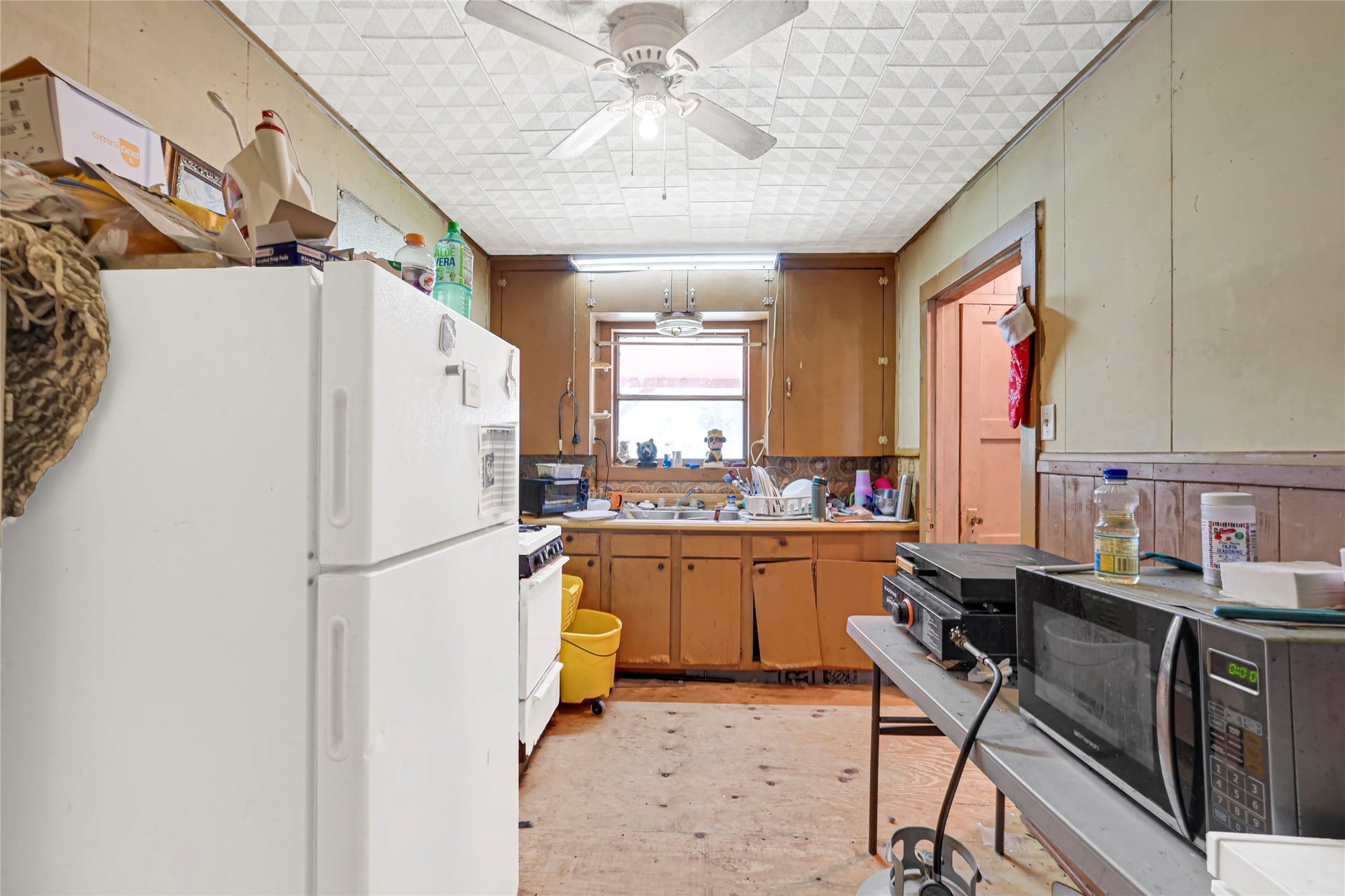 121 Patterson Road, #CR814, Brazoria, TX 77422 Cozy kitchen with ample cabinet space, featuring a ceiling fan and natural light from a central window, offering potential for customization.