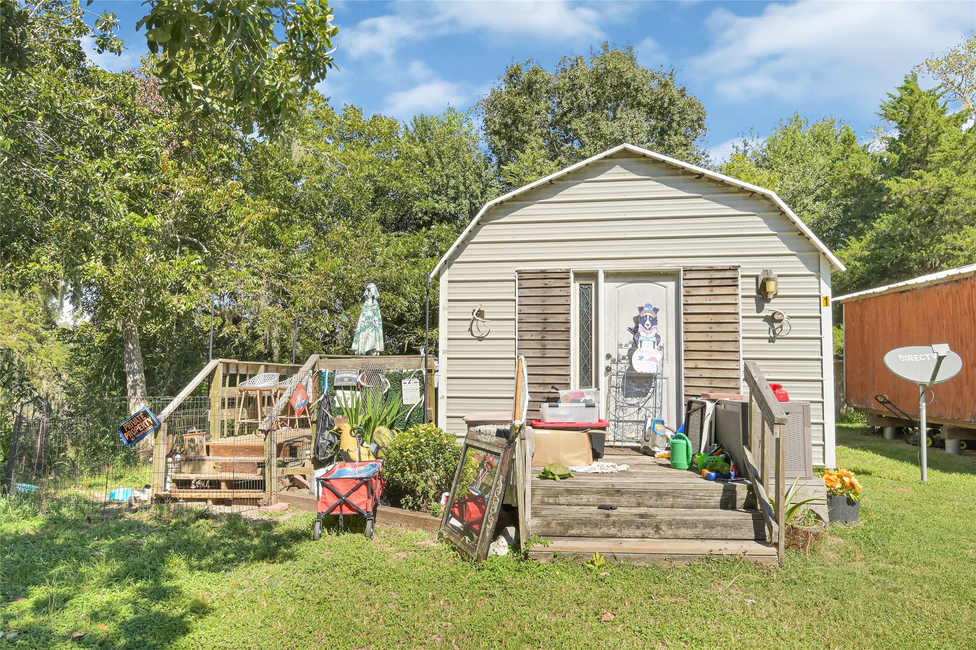 121 Patterson Road, #CR814, Brazoria, TX 77422 Charming rustic cottage surrounded by lush greenery, featuring a cozy porch perfect for outdoor relaxation and entertainment.