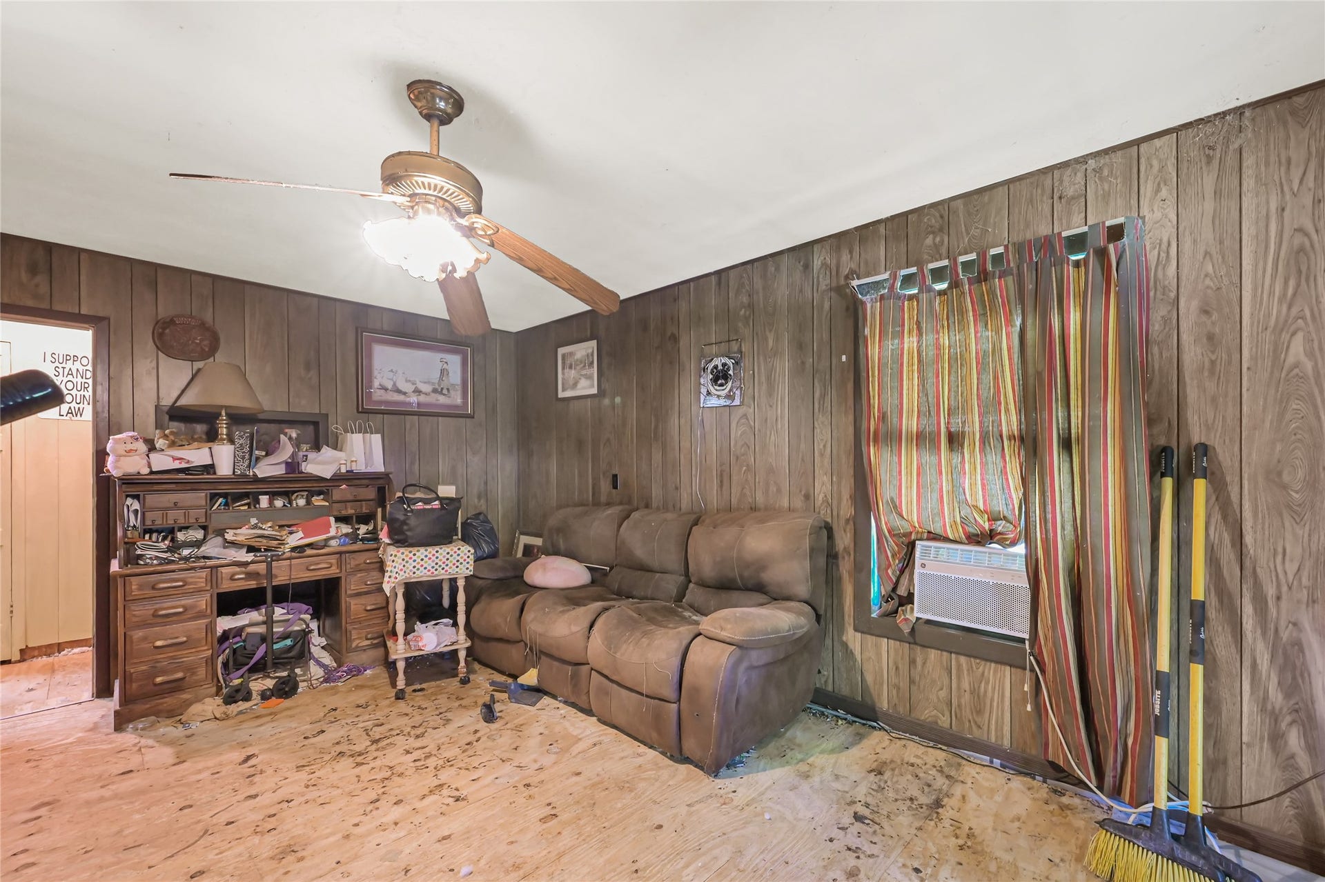 121 Patterson Road, #CR814, Brazoria, TX 77422 Cozy room featuring wood paneling, a comfortable recliner sofa, and a ceiling fan, offering a rustic charm.