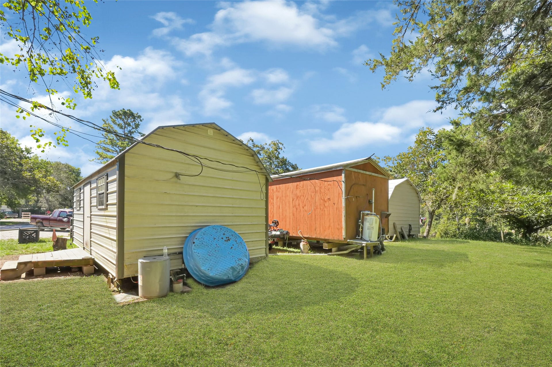 121 Patterson Road, #CR814, Brazoria, TX 77422 Spacious backyard with multiple storage sheds, surrounded by mature trees for added privacy and shade.