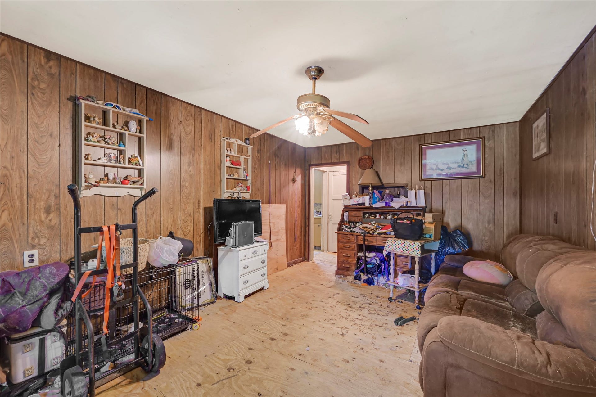 121 Patterson Road, #CR814, Brazoria, TX 77422 Cozy living space with wood paneling, ceiling fan, and potential for customization.