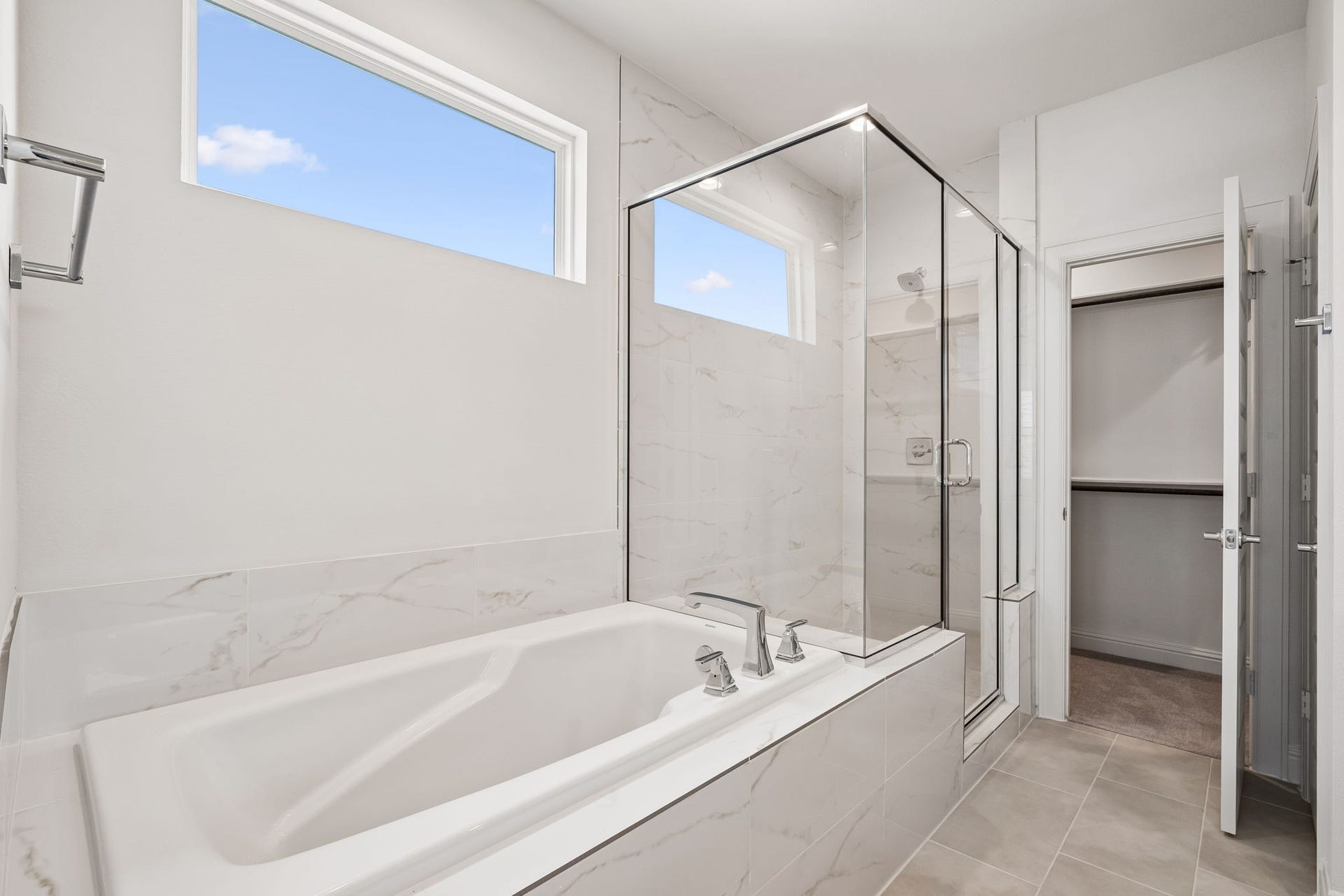 Luxuriate in the elegant primary bathroom featuring a sleek glass-enclosed shower and a spacious soaking tub, all framed by modern, light-filled design.