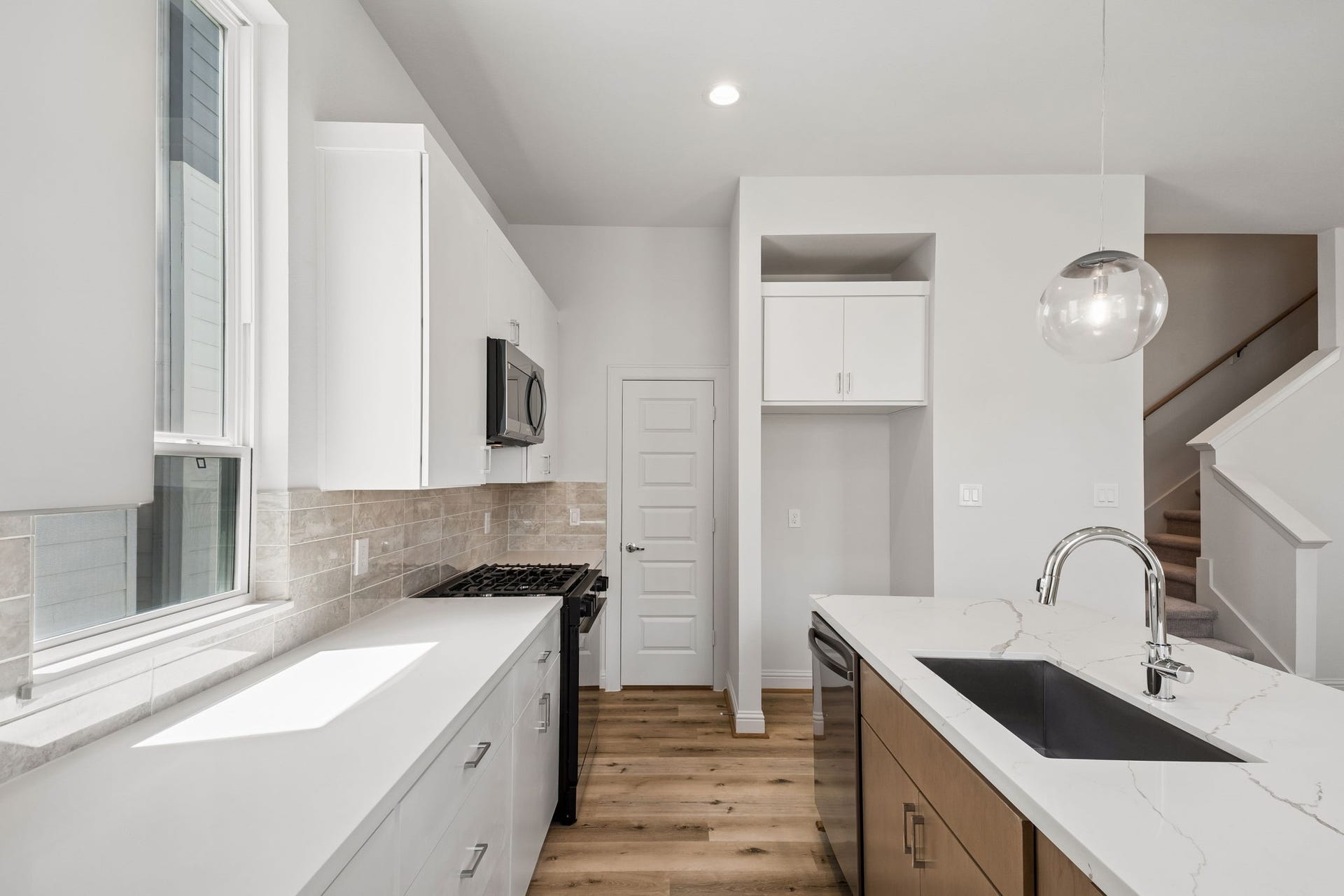 Sleek and modern kitchen with abundant natural light, featuring a spacious pantry for all your storage needs.