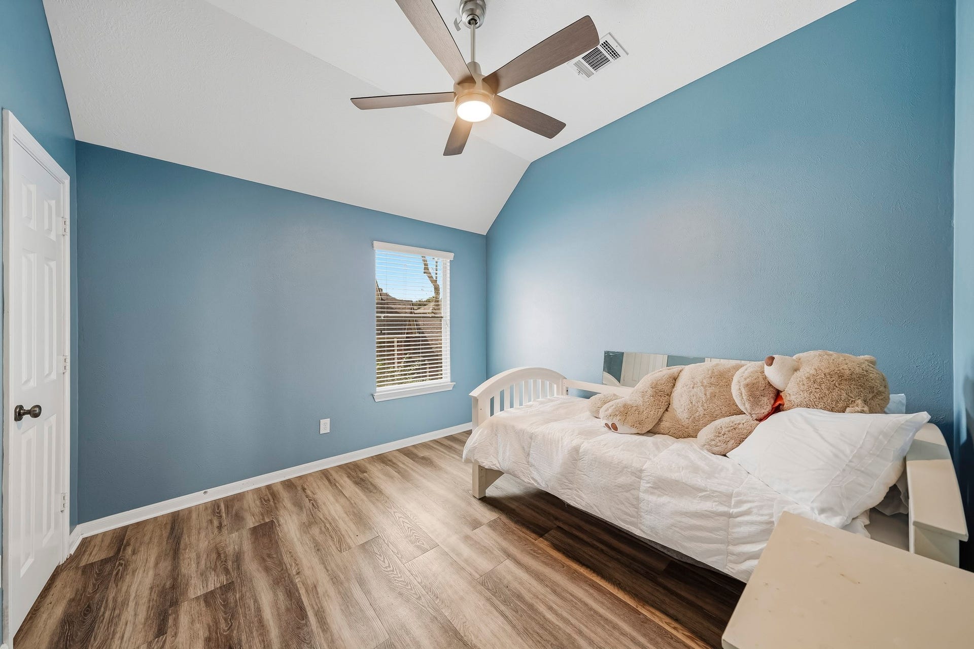 5507 Sandy Trace Court, Katy, TX 77494 Another inviting upstairs bedroom features a cheerful blue accent wall, wood-look flooring, and a ceiling fan. A window brightens the space, while the comfortable dimensions make it equally suitable as a bedroom, home office, or creative retreat.