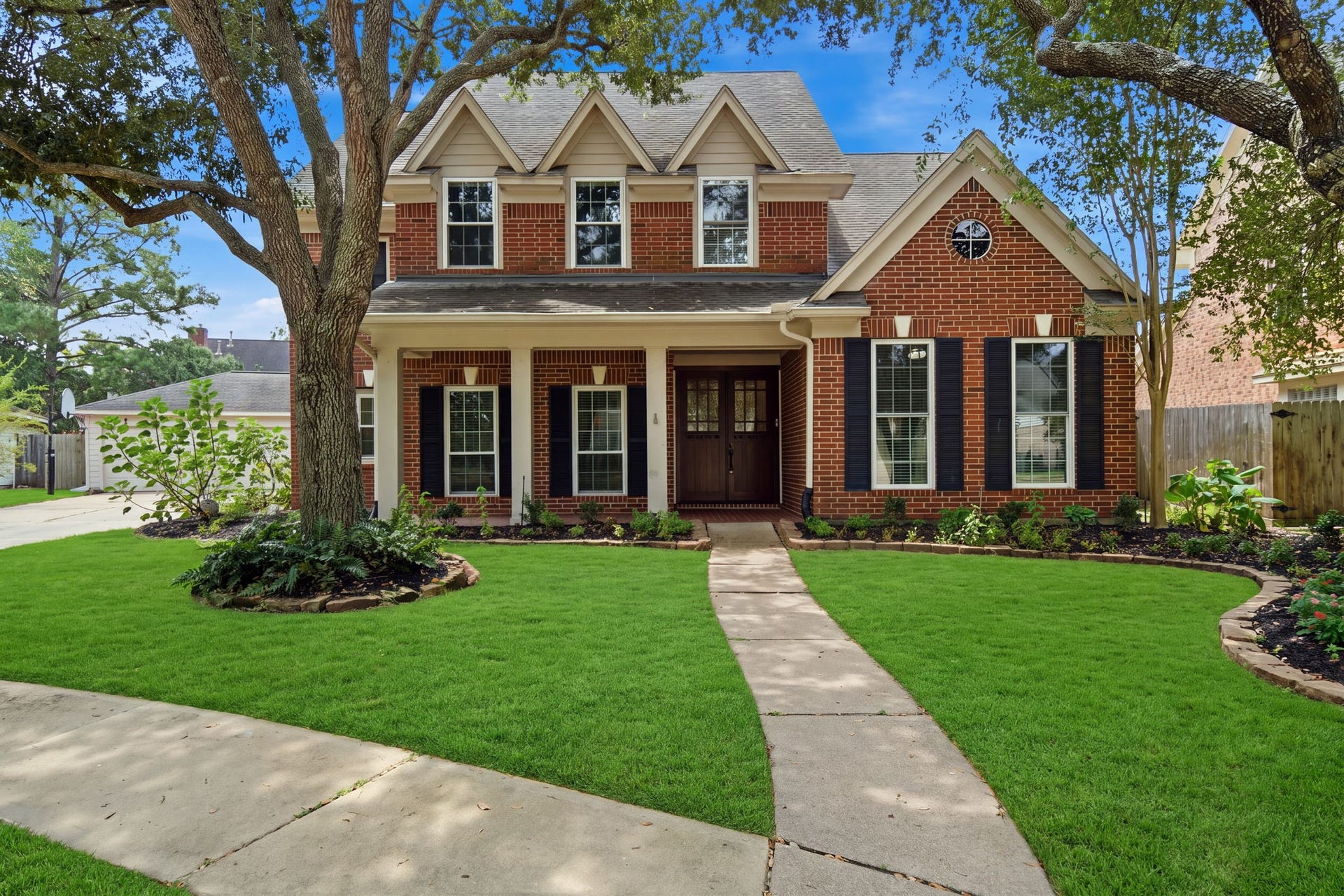 2214 Lytham Lane, Katy, TX 77450 Charming brick home with a classic gabled roof and inviting front porch, nestled amidst lush greenery and mature trees. Located on cul-de-sac street with golf course view.