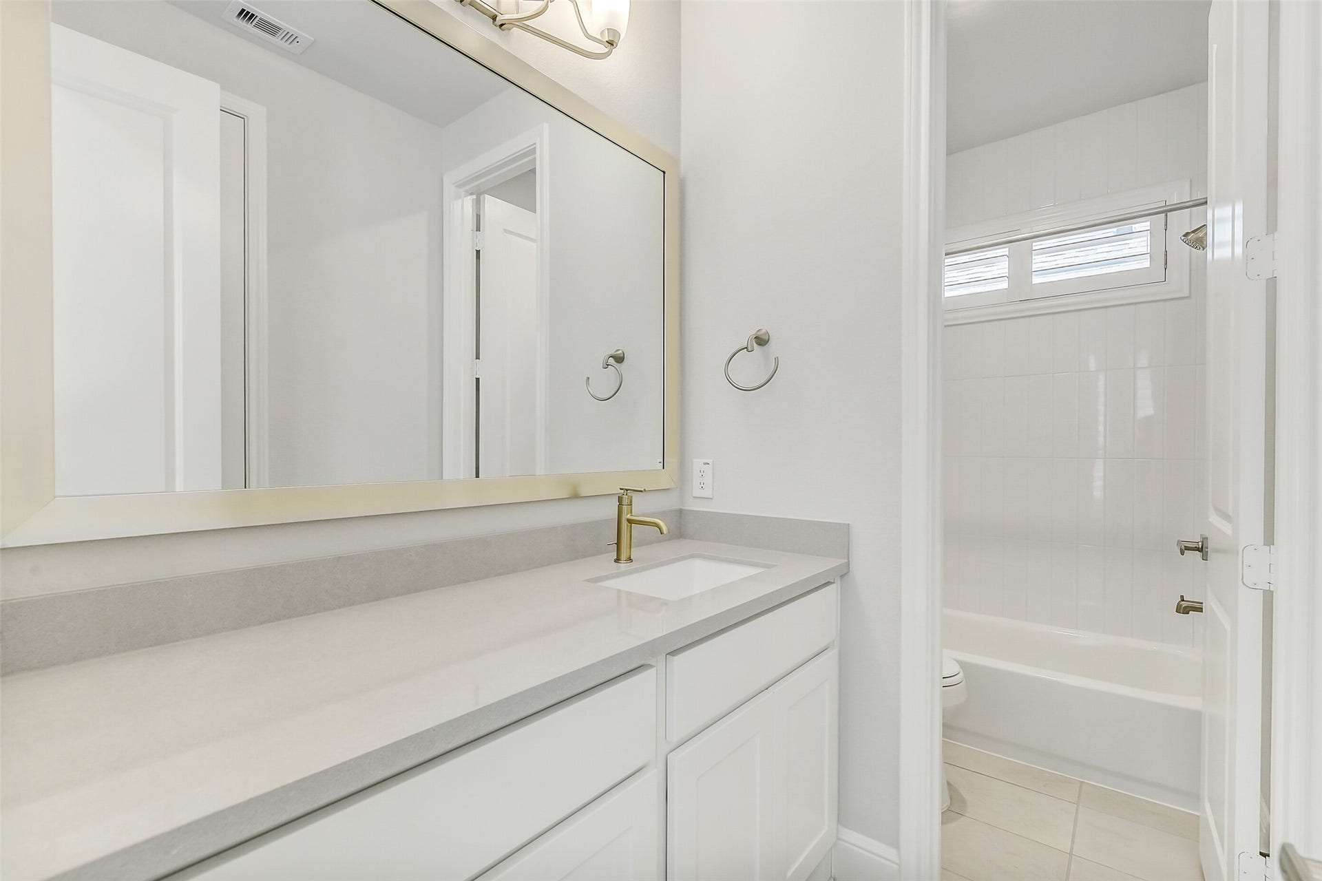 The second bathroom with tile flooring and marble vanity countertop