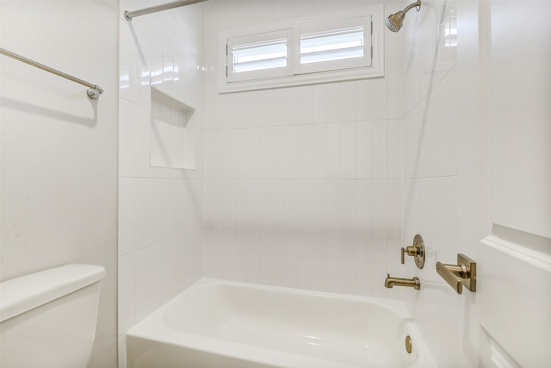 The bath has tile surround and an inset in the wall to hold the soap and shampoo. Notice the Sunburst shutters on the windows.