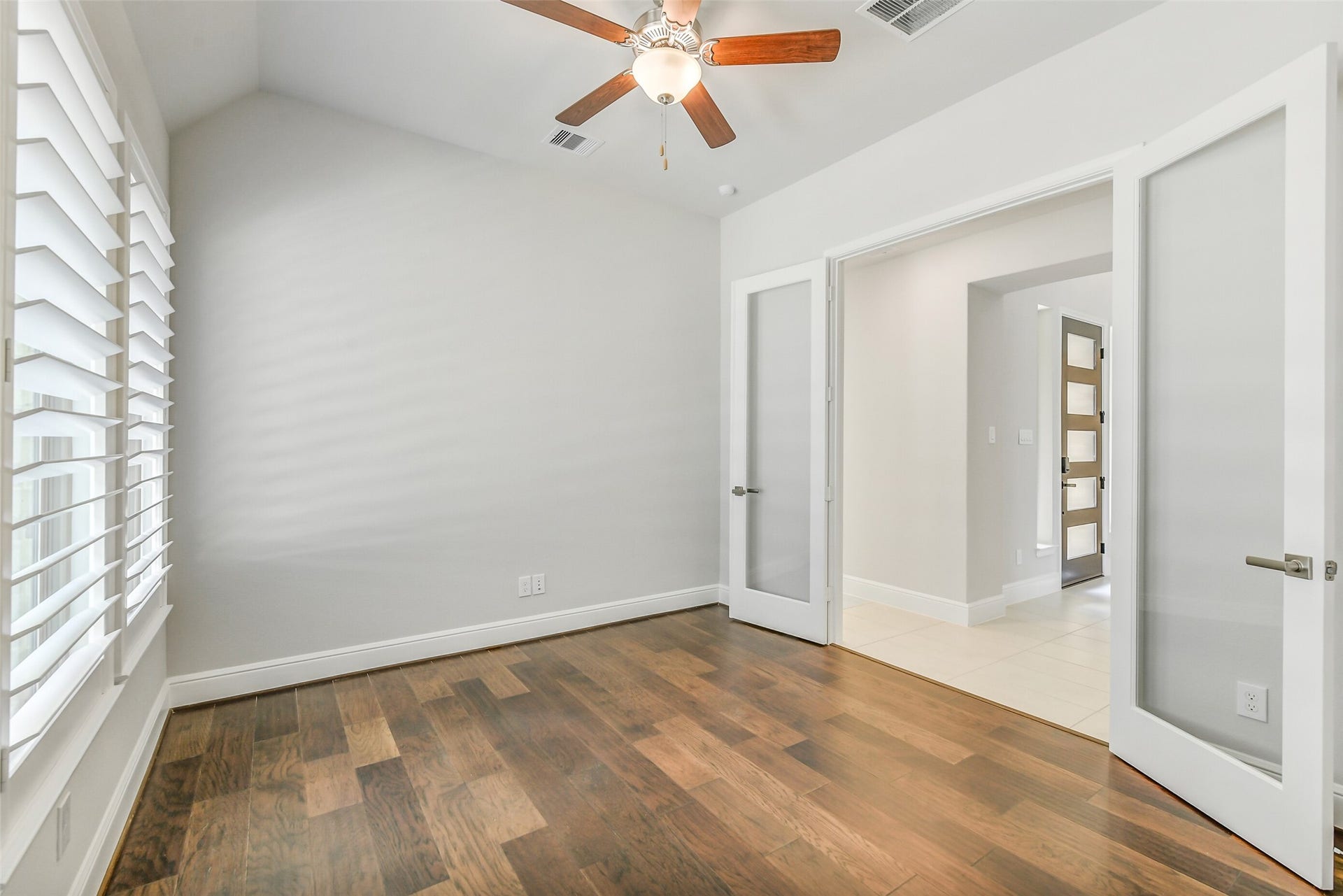 The study has Wood flooring and plantation shutters on the windows.