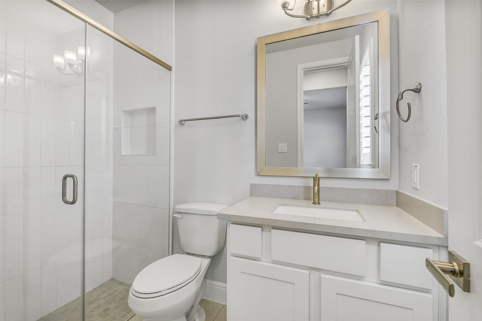 Private bath for bedroom three has glass enclosed shower.