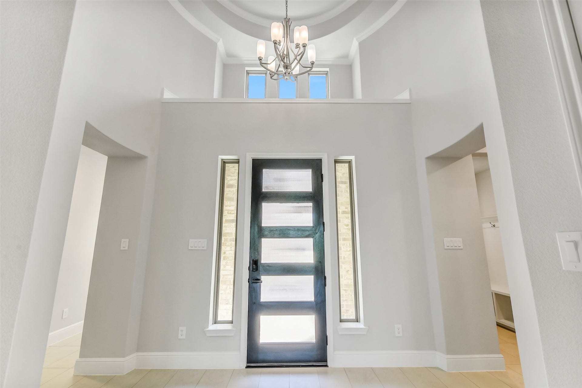 Beautiful entry way with decorative shelf and rotunda with chandelier that leads to the open living area.