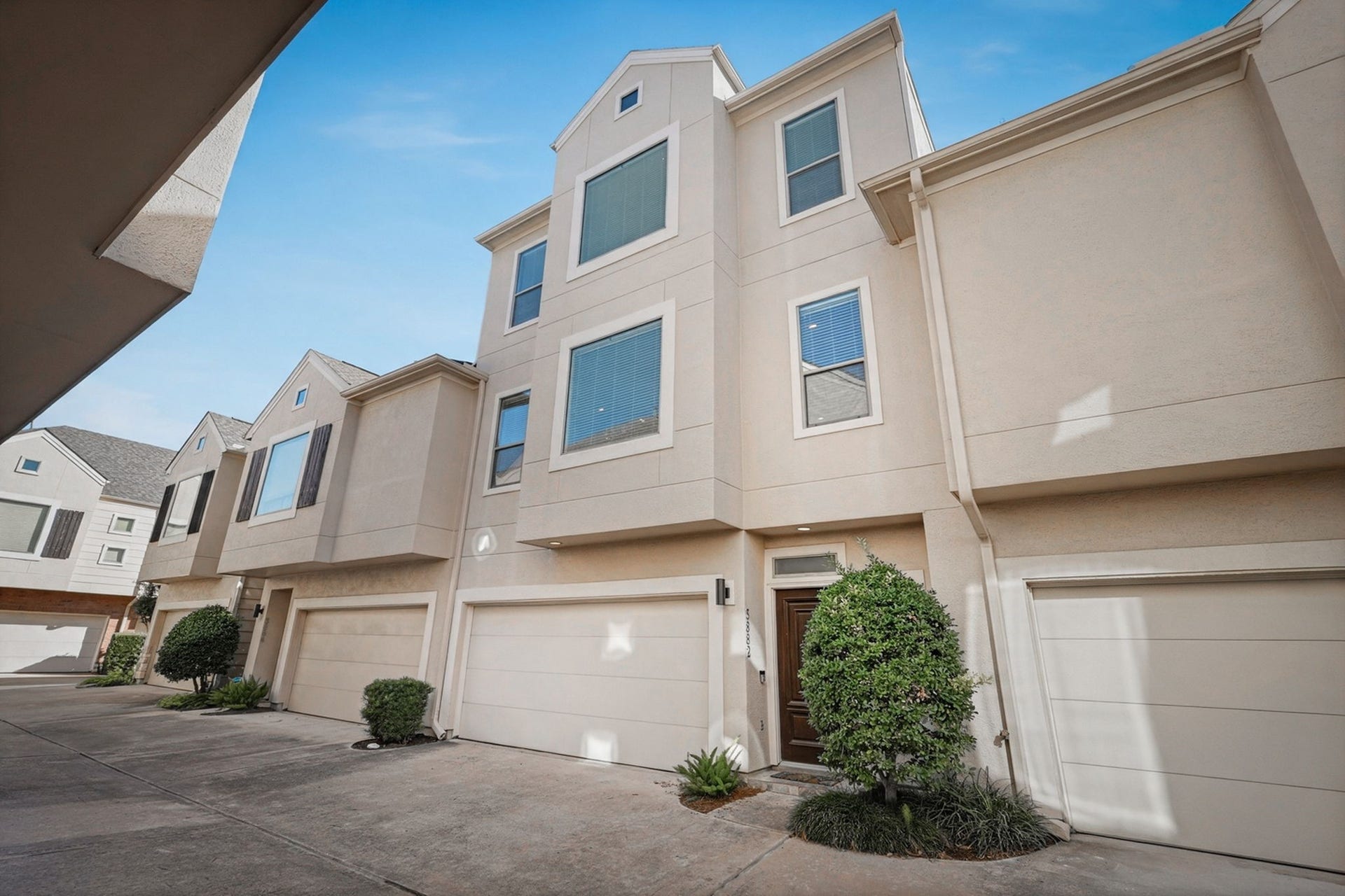 3882 Center Street, Houston, TX 77007 Attractive three-story townhome featuring a stucco exterior, attached garage, and landscaped front entry in a courtyard-style community