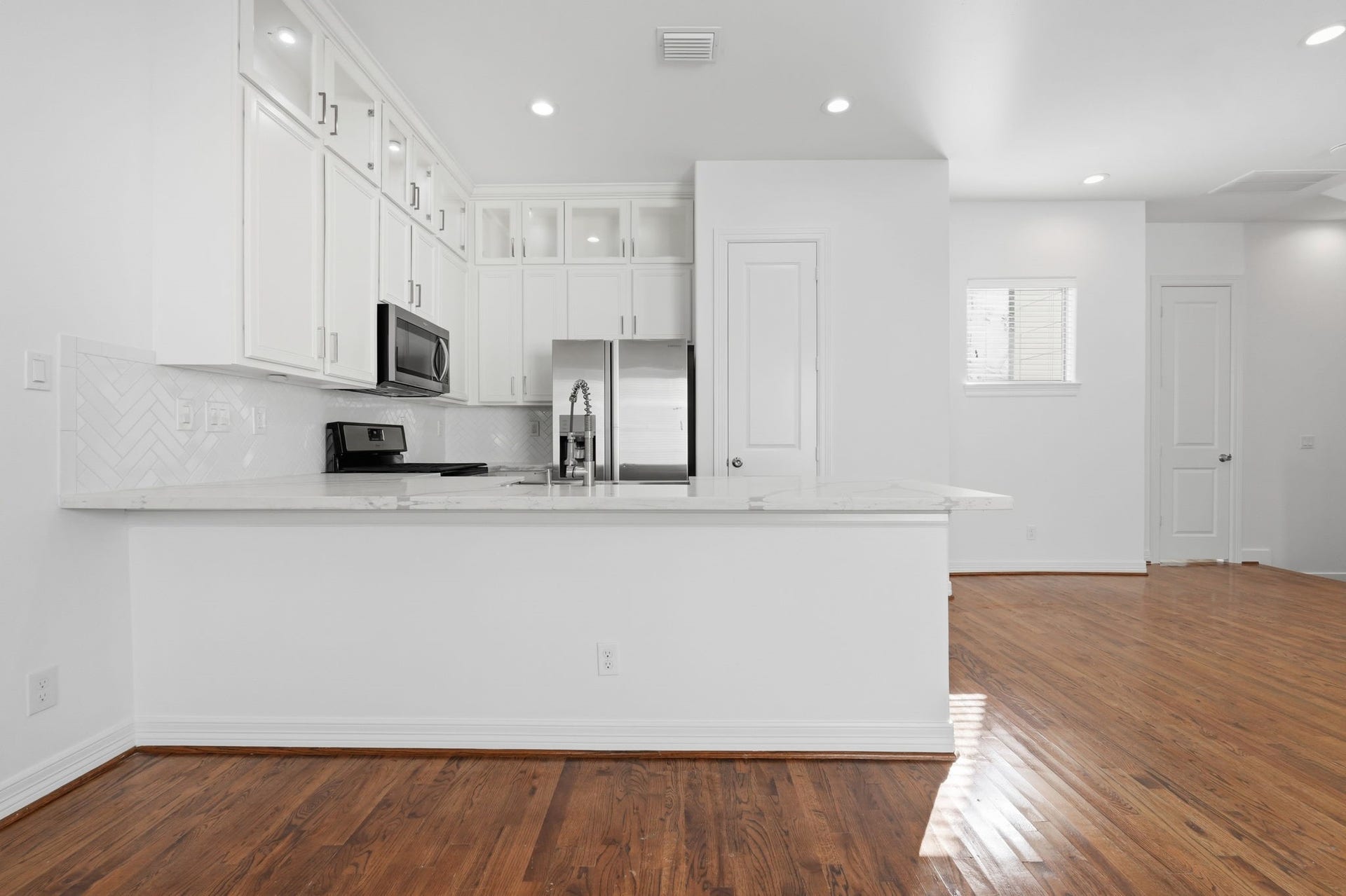 3882 Center Street, Houston, TX 77007 A thoughtfully designed kitchen features ceiling-height cabinetry, a decorative herringbone backsplash, and generous counter space, with stainless steel appliances and a breakfast bar that seamlessly connects to the surrounding living area. (2nd floor)