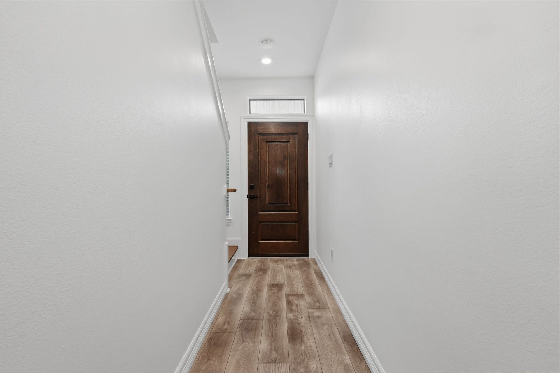 3882 Center Street, Houston, TX 77007 The hallway features crisp white walls, recessed ceiling lighting, and a rich wood door at the end, creating a clean, streamlined transition between living spaces.