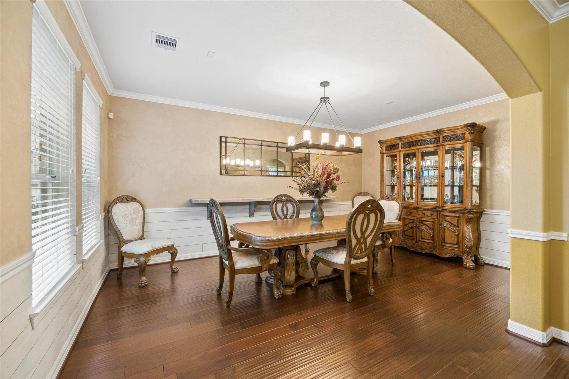 24935 Waterstone Estates Circle W, Tomball, TX 77375 An elegant formal dining room offers a refined setting for memorable gatherings, featuring rich hardwood floors, crown molding, abundant natural light, a stylish faux accent wall, and timeless architectural details that enhance its sophisticated appeal.