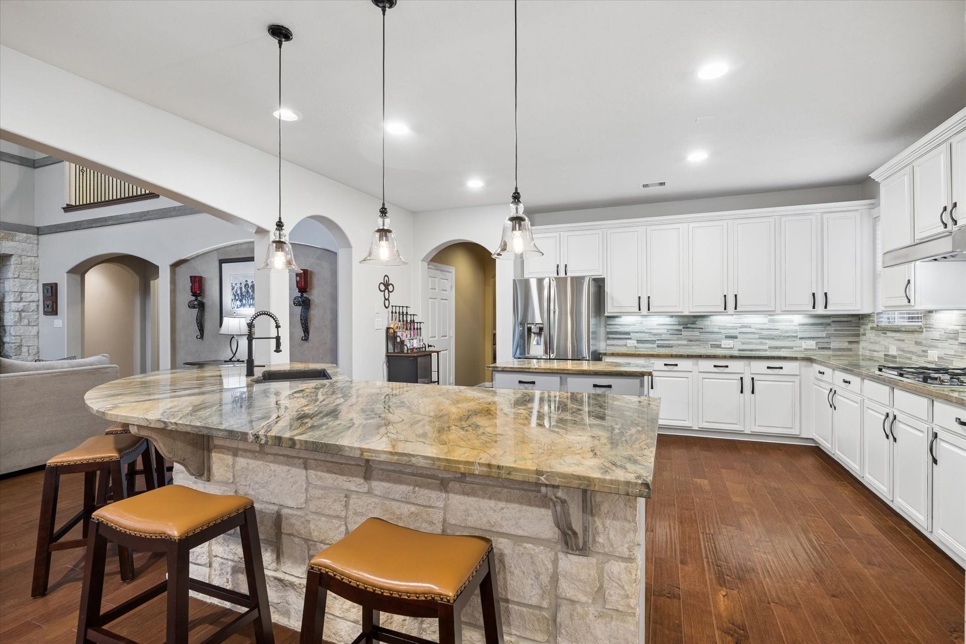 24935 Waterstone Estates Circle W, Tomball, TX 77375 Designed for gathering and entertaining, the expansive kitchen features a generous breakfast bar with seating, beautiful stone accents, abundant cabinetry, and extensive counter space. Pendant lighting adds warmth and character, while the open design creates a natural connection to the family room.