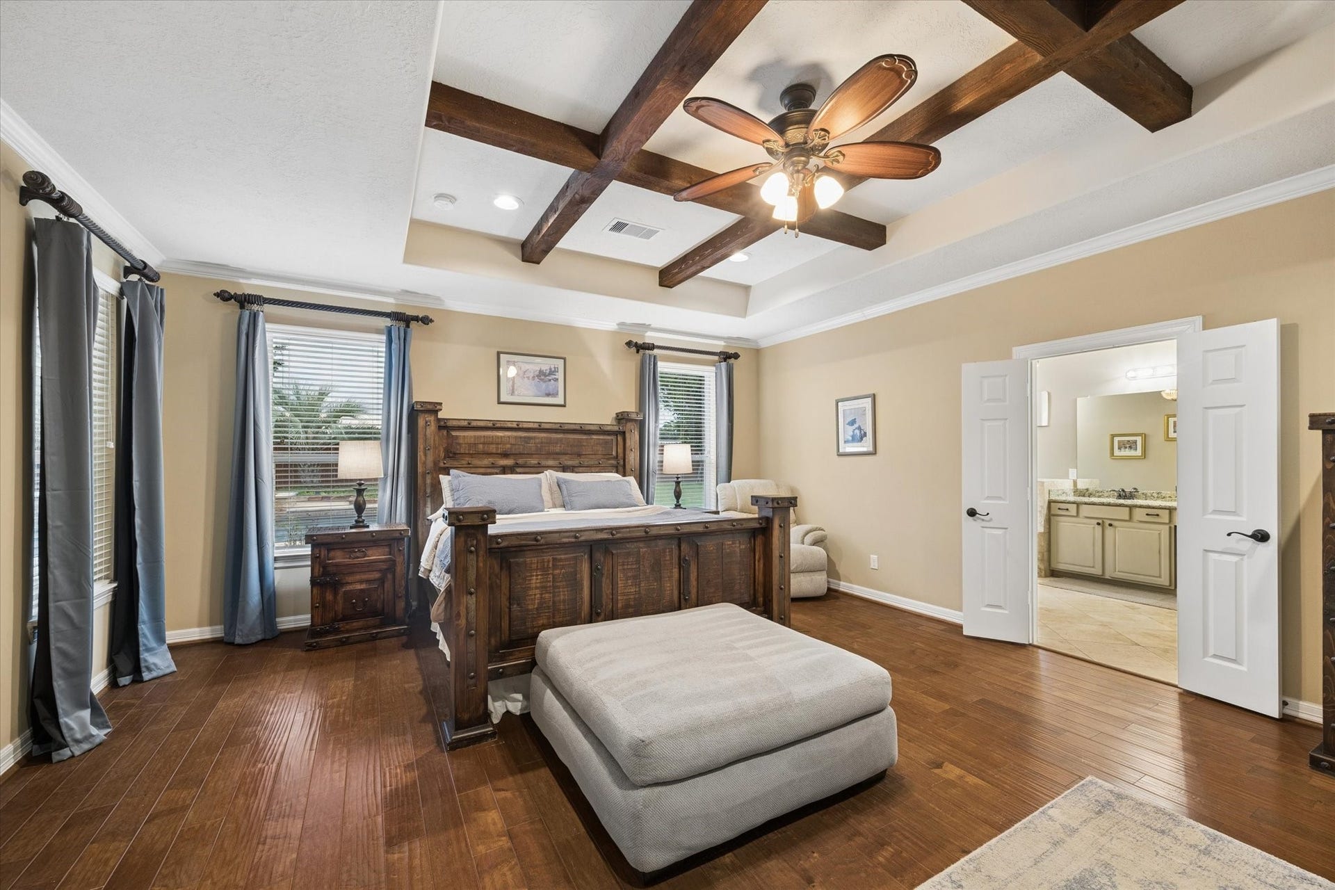 24935 Waterstone Estates Circle W, Tomball, TX 77375 The generously sized primary suite offers a warm and inviting retreat, highlighted by beautiful wood flooring, abundant natural light, and a distinctive tray ceiling accented with exposed wood beams. Double doors provide a gracious entrance to the en-suite bath, completing this comfortable and private space.