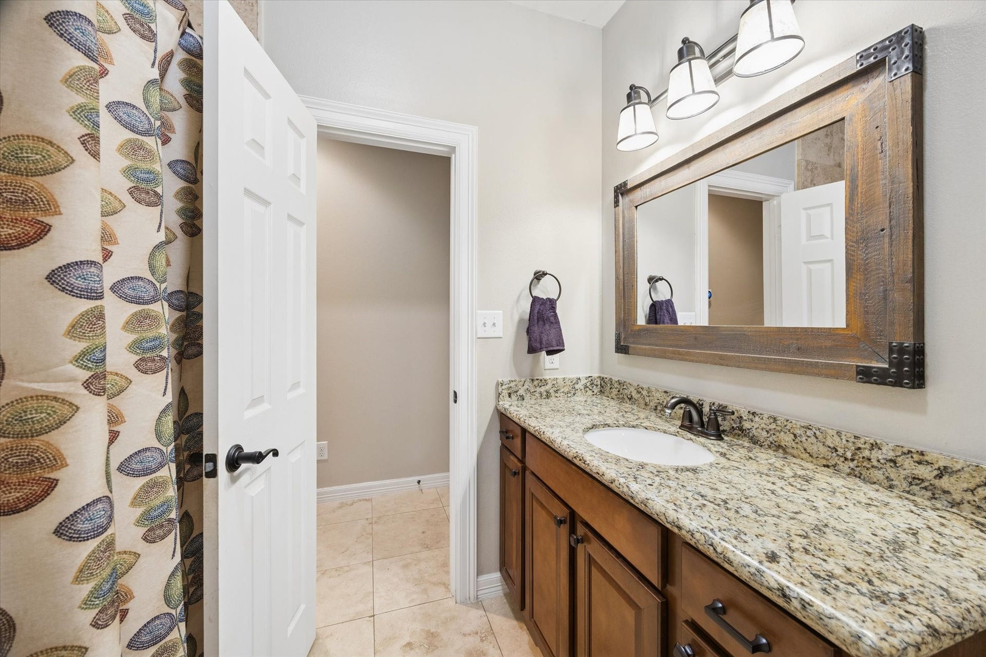 24935 Waterstone Estates Circle W, Tomball, TX 77375 A well-appointed secondary bathroom on the first floor features a granite countertop, warm wood cabinetry, and a practical layout, offering comfort and convenience for family members or guests.