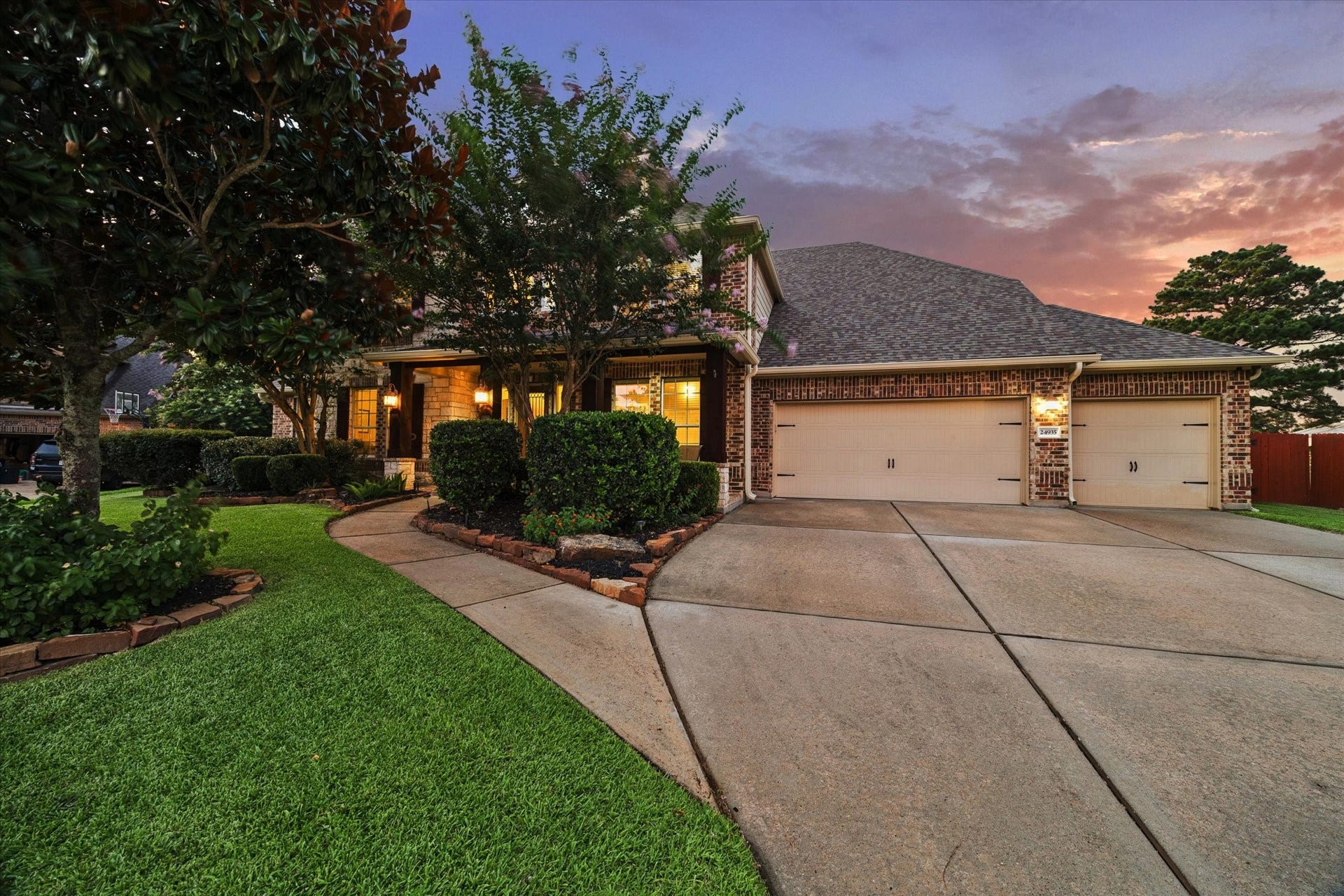 24935 Waterstone Estates Circle W, Tomball, TX 77375 A spacious driveway leads to the three-car garage and welcoming front entrance, beautifully framed by lush landscaping and the homes timeless architectural details.