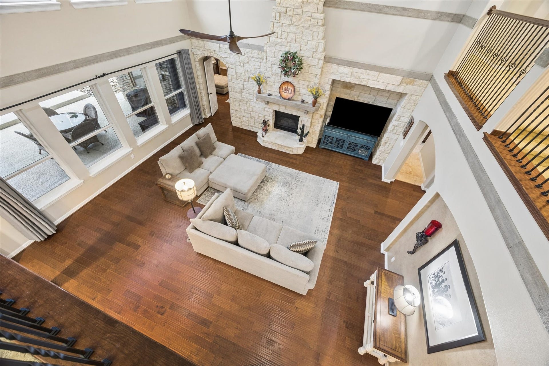 24935 Waterstone Estates Circle W, Tomball, TX 77375 An impressive view from the second level overlooks the expansive family room, showcasing the homes soaring ceilings, beautiful wood flooring, striking stone fireplace, and abundant natural light. The open design and architectural details create a remarkable sense of space and connection throughout the home.