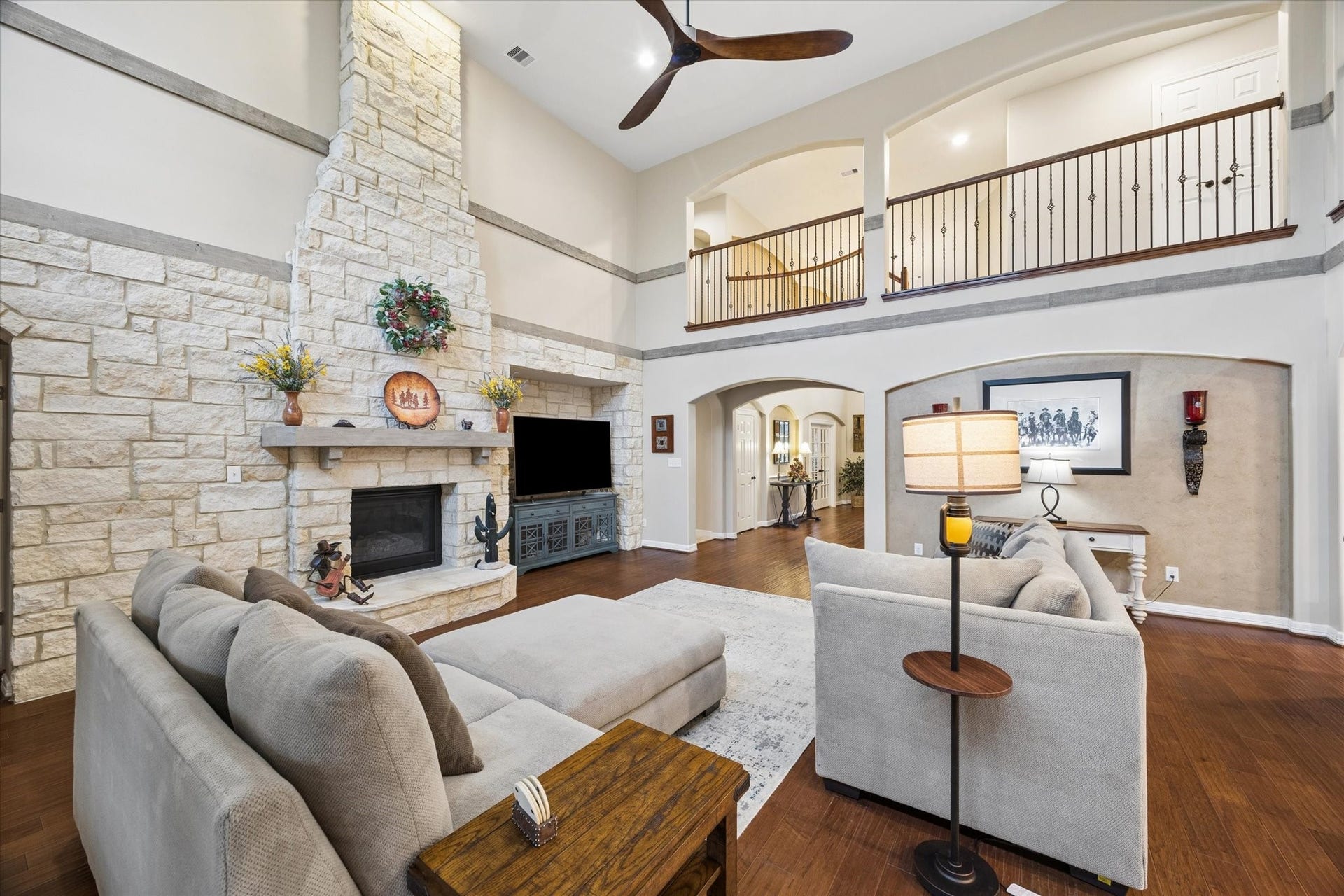 24935 Waterstone Estates Circle W, Tomball, TX 77375 A dramatic floor-to-ceiling stone fireplace creates a striking focal point in the expansive family room. Soaring ceilings, rich hardwood floors, and views of the second-level gallery enhance the homes impressive sense of space and architectural character.