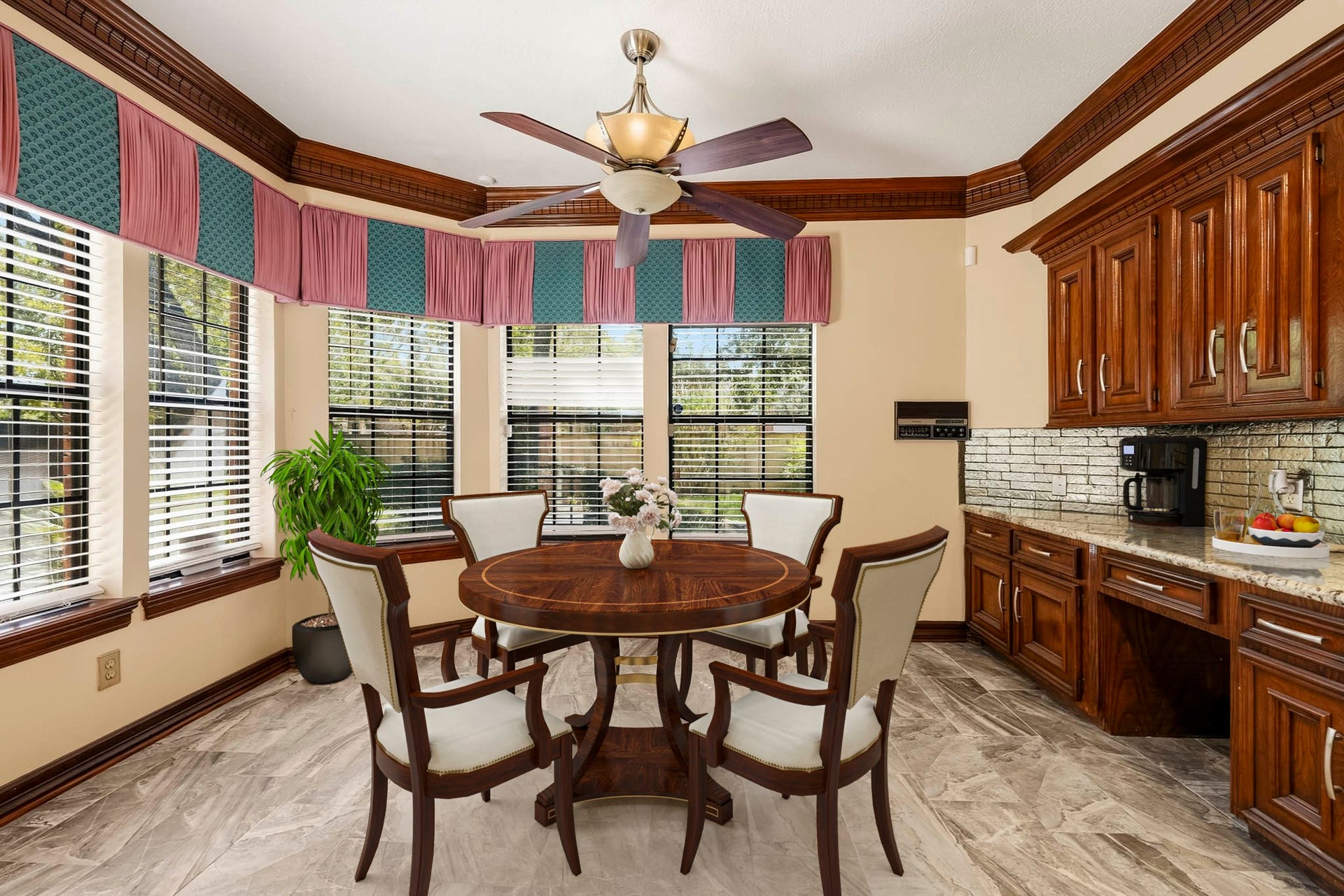 Virtually Staged: Charming breakfast space framed by large windows! Outfitted with built-in cabinetry, granite counter space, a built-in desk area, and a ceiling fan.
