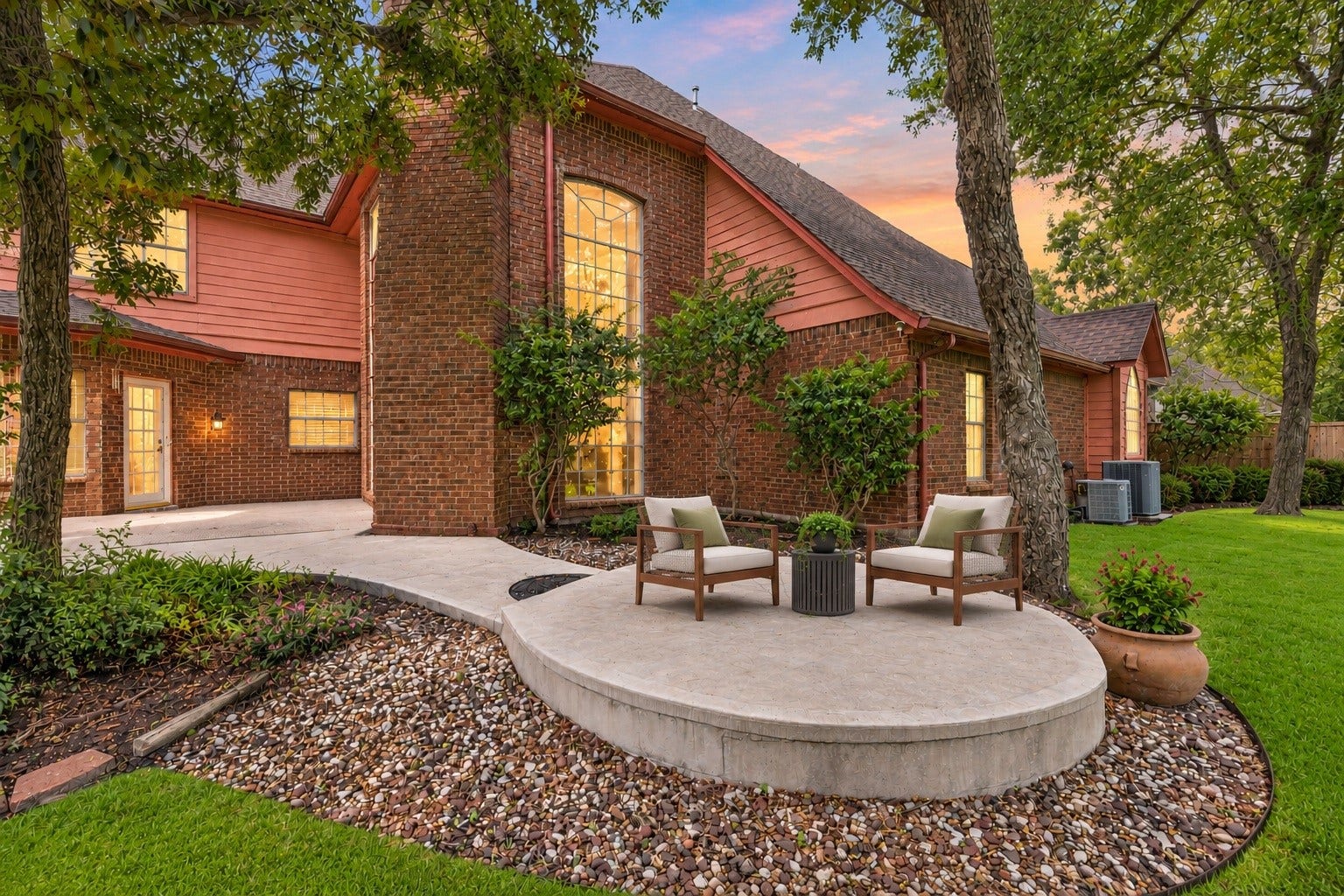 Virtually Staged: Dynamic rear patio view emphasizing the homes grand architectural details, including tall floor-to-ceiling multi-pane windows and a red-brick facade.