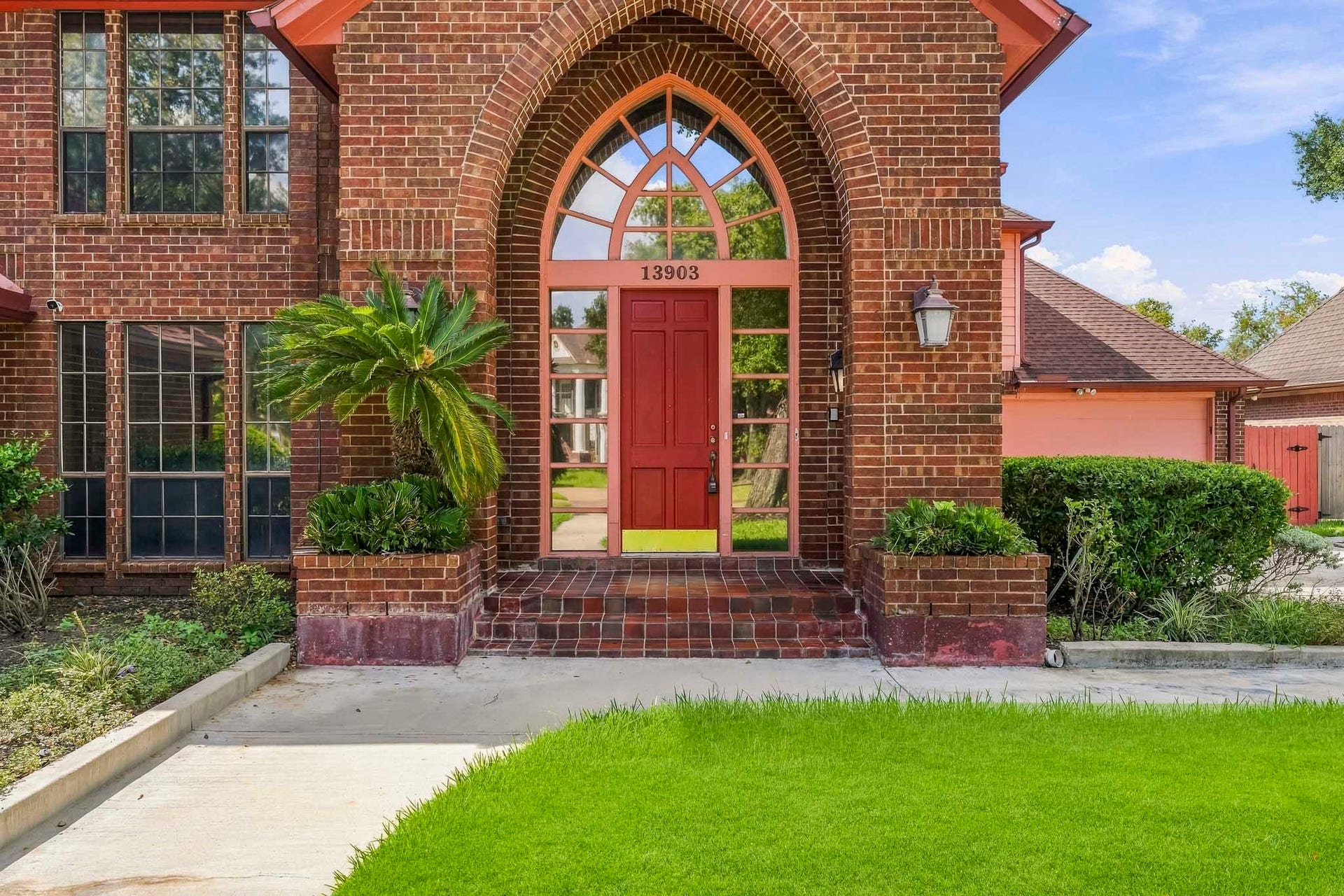 Make a unforgettable first impression! This close-up highlights the home's grand arched entry, rich brickwork, and sunlit entryway glass framing an inviting front door.
