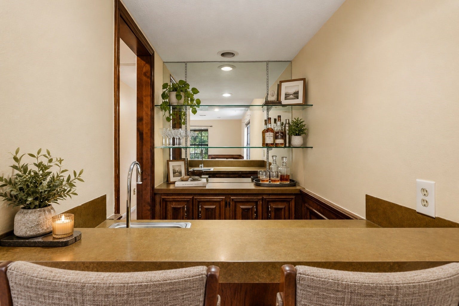 Virtually Staged: Built-in wet bar perfect for entertaining! Complete with a stainless steel prep sink, pass-through counter, custom wood cabinetry, mirrored wall, and adjustable display track lighting.