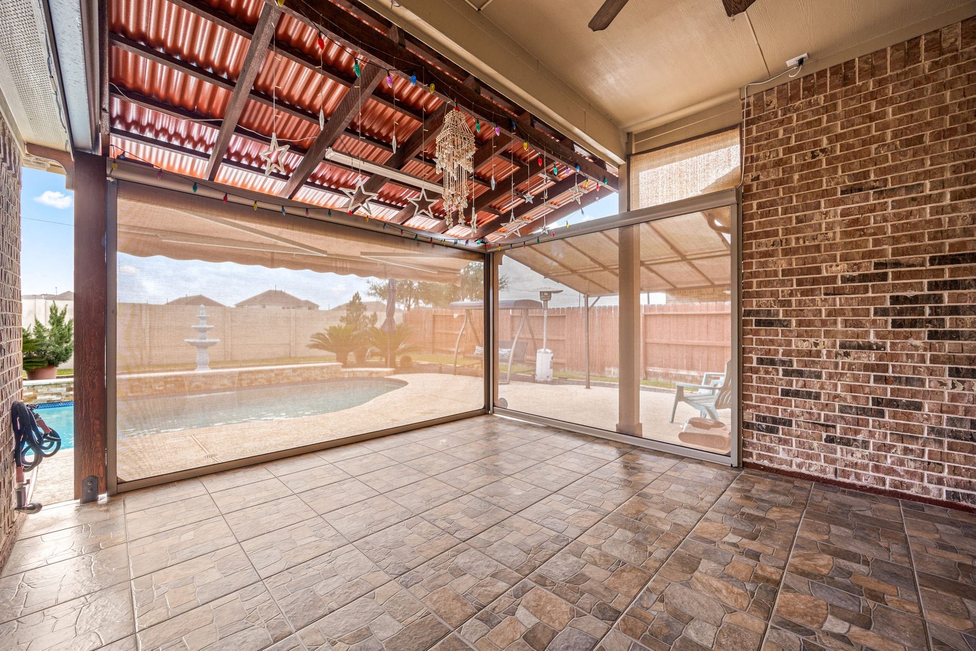 An alternate view of the outdoor living space showcasing the retractable privacy screensperfect for keeping the patio cool on warm Texas afternoons while enjoying views of your sparkling pool.