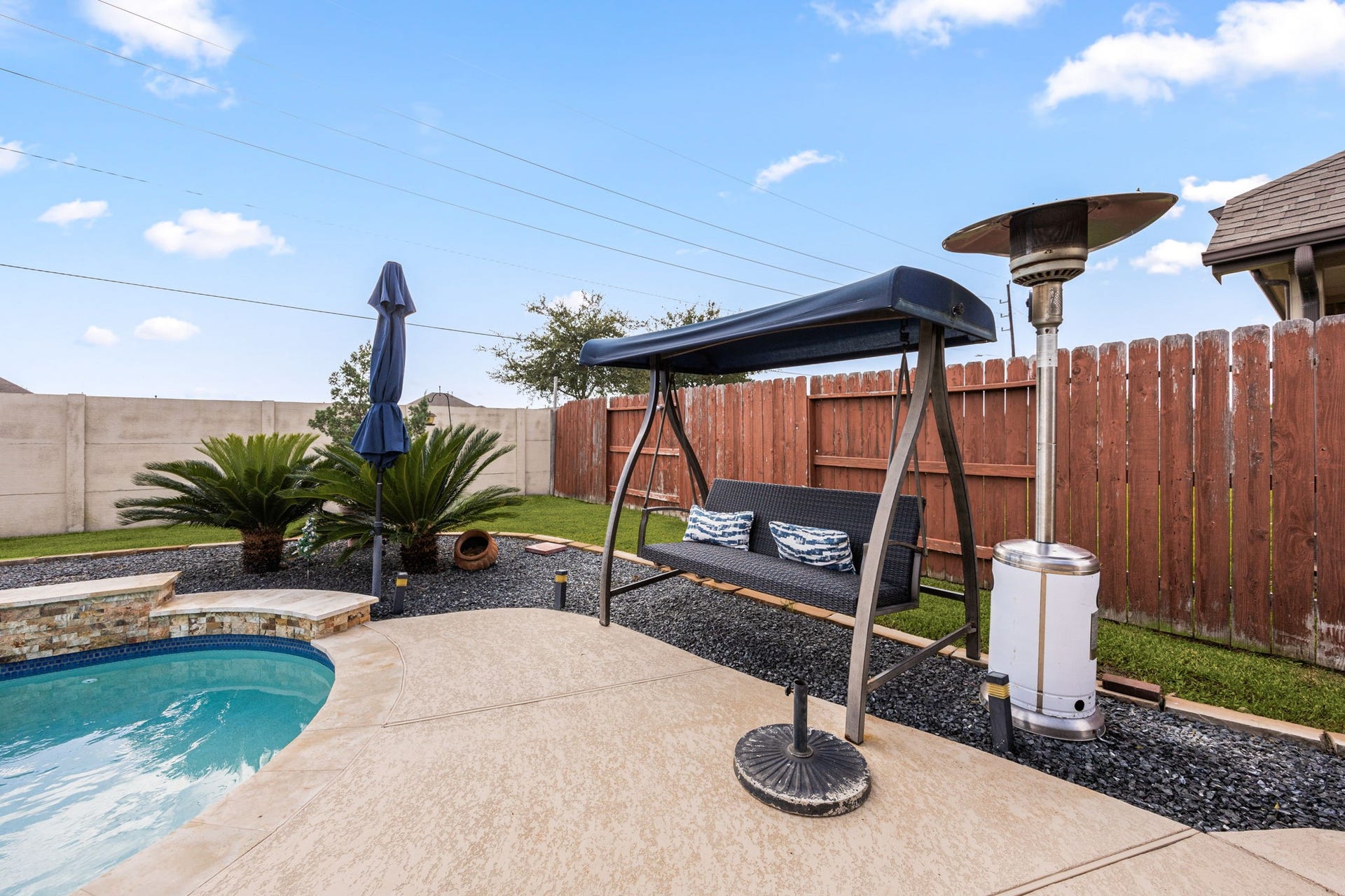 This charming seating area showcases low-maintenance rock landscaping beds, a spacious pool decking layout, and a highly durable, solid concrete back fence line ensuring lasting privacy. NOTE: NO BACK NEIGHBORS!