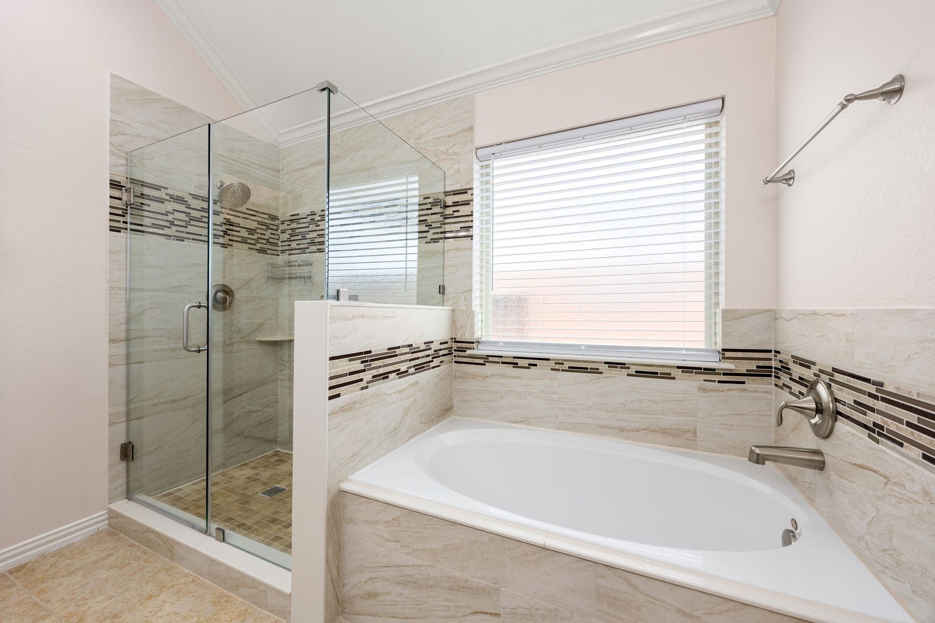 Spa-like primary bath retreat featuring a deep soaking tub and a separate frameless glass walk-in shower, both beautifully detailed with custom tile surrounds and decorative mosaic accents.