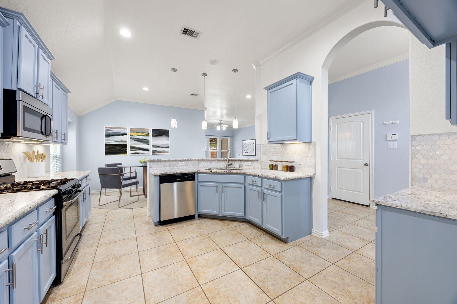 This expansive viewpoint highlights the functional kitchen layout, featuring subtle under-cabinet task lighting and dual entry points for seamless traffic flow into the main living areas. *Virtually Staged