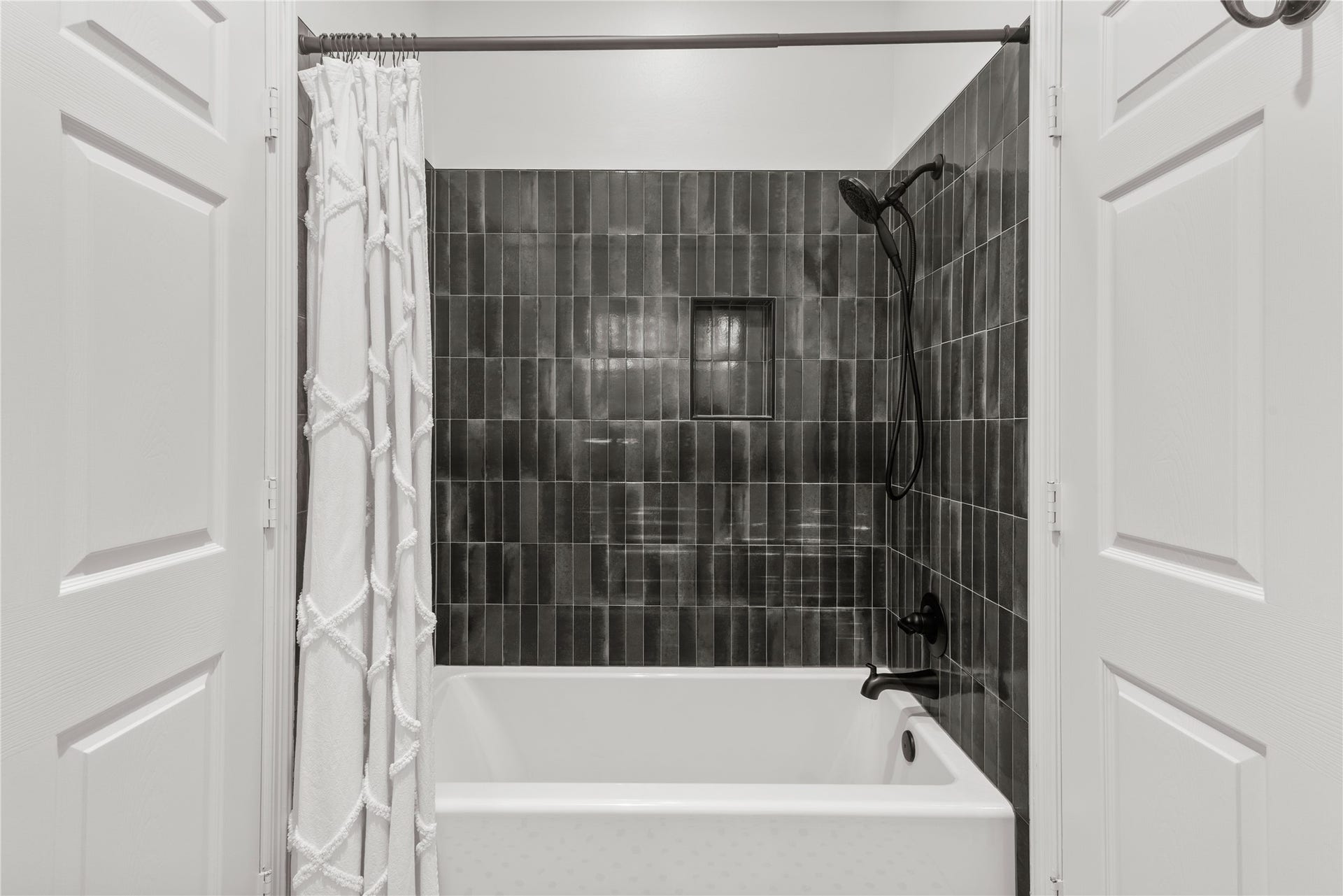 901 Longmire Road, #51, Conroe, TX 77304 Freshly updated tub and shower surround featuring striking charcoal tile, sleek matte-black fixtures & a built-in niche for a sophisticated, modern finish.