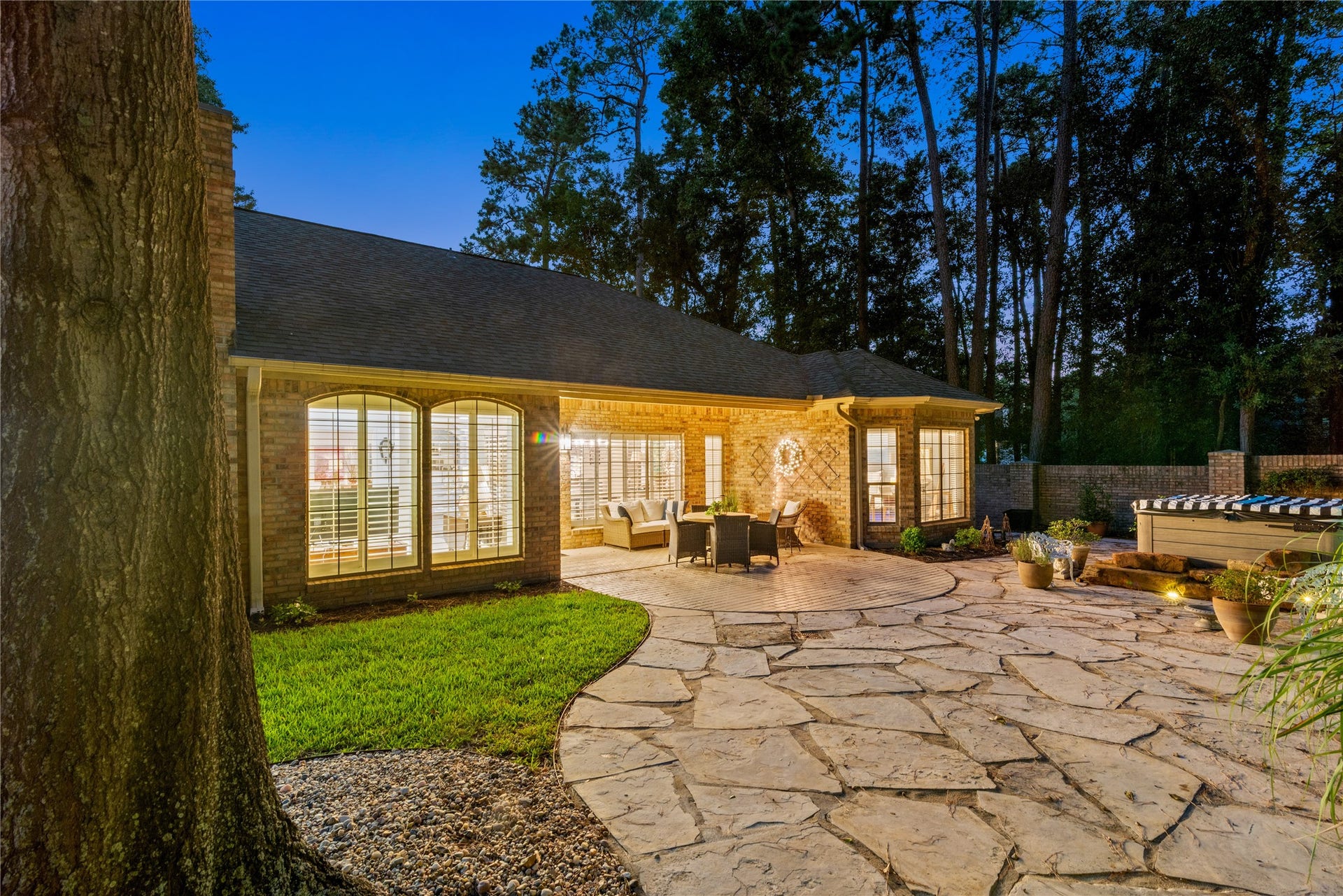 901 Longmire Road, #51, Conroe, TX 77304 An enchanting backyard retreat featuring an expansive natural stone patio, elegant outdoor lighting, relaxing Jacuzzi & towering pines. The perfect setting for intimate gatherings or peaceful evenings under the stars.
