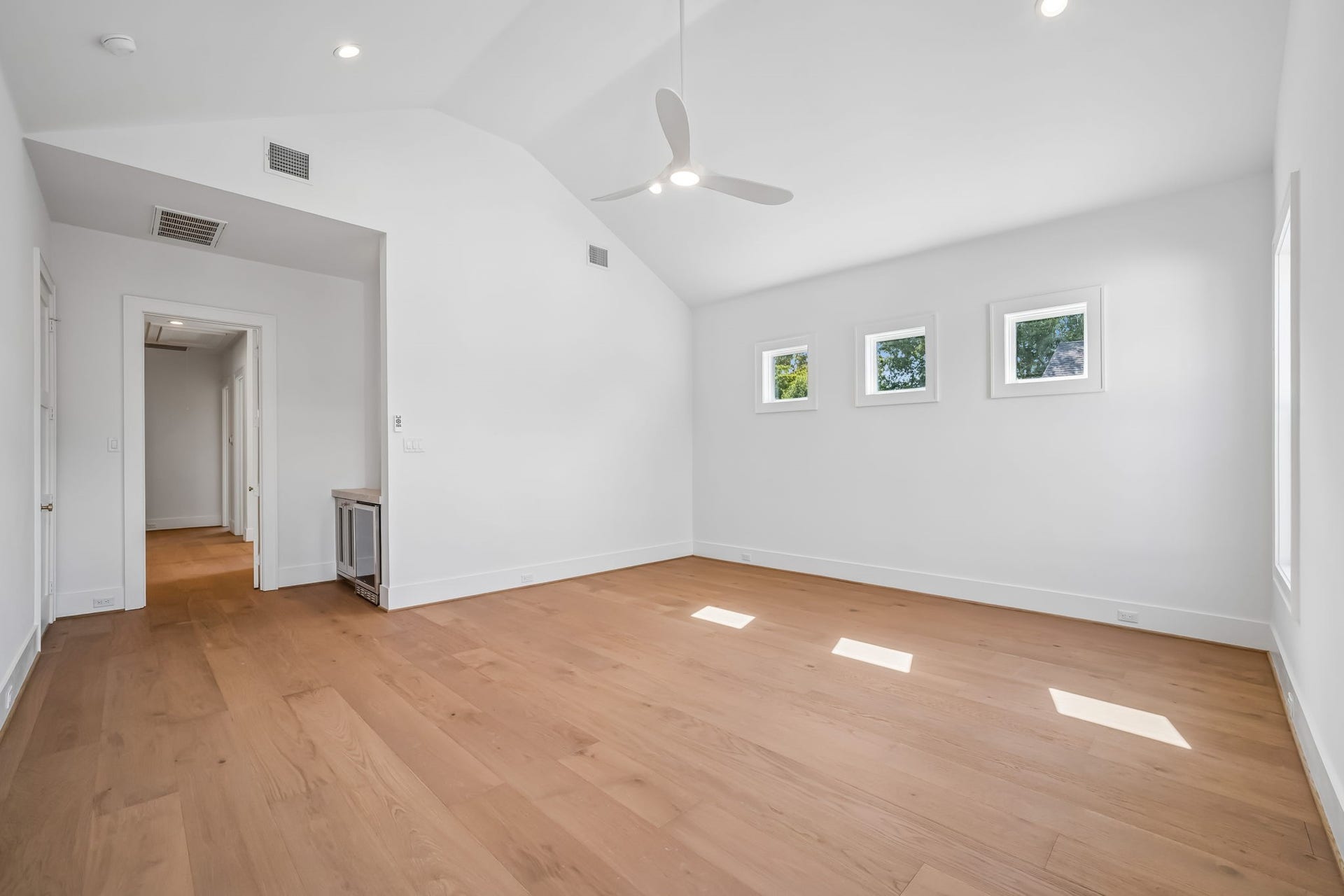 Second-floor primary suite featuring vaulted ceilings and the added luxury of a private beverage refrigerator.