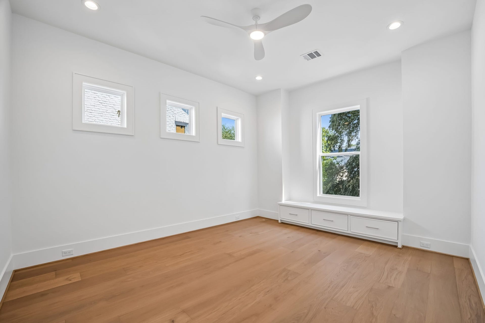 Another second-floor bedroom featuring built-in drawers beneath the front-facing window for added storage.