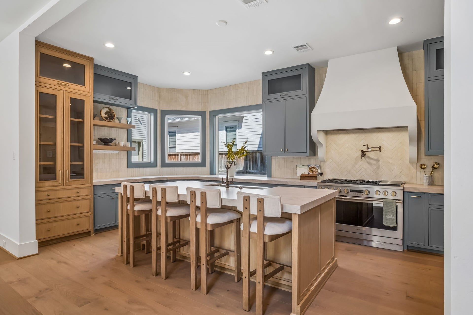 Take a look at the stunning custom stucco vent hood, perfectly positioned above the 48-inch gas range and complemented by a copper pot filler. The oversized island is equally thoughtful, offering additional storage on both ends along with plenty of seating for gathering, entertaining, and everyday living.