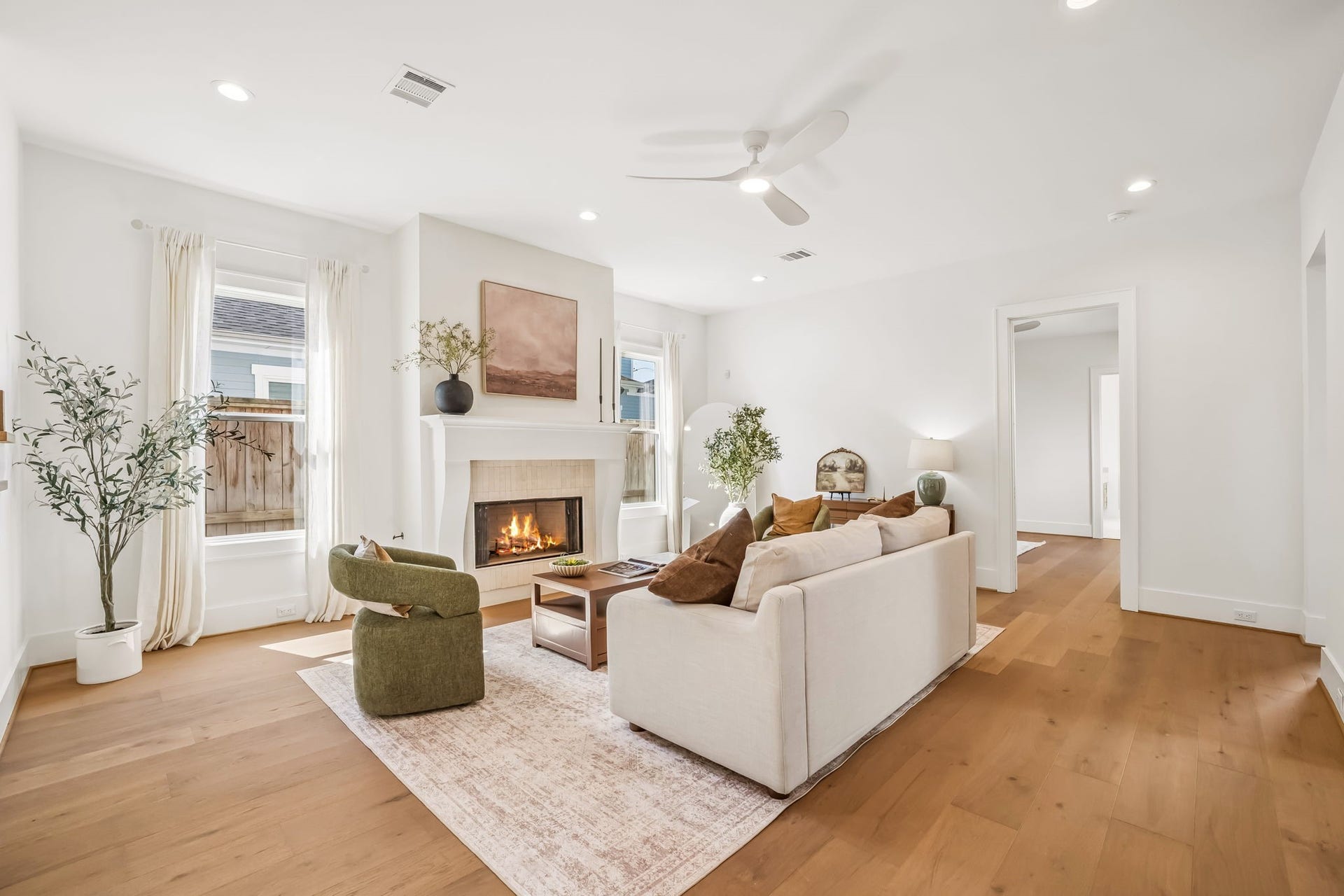 Bright, open-concept living room featuring a neutral palette, comfortable seating, and warm wood floors.