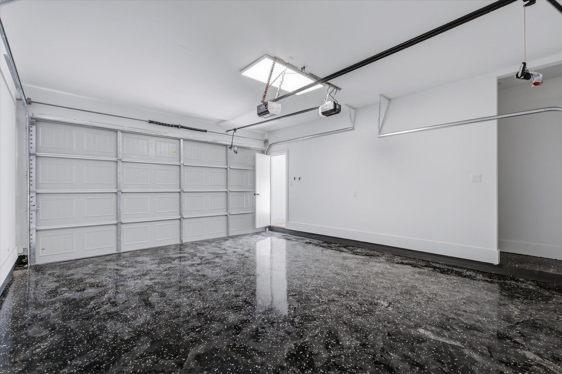 A thoughtfully designed garage offers dual motorized doors for seamless access from both the alley and private portico, complete with sleek epoxy flooring for a polished finish.