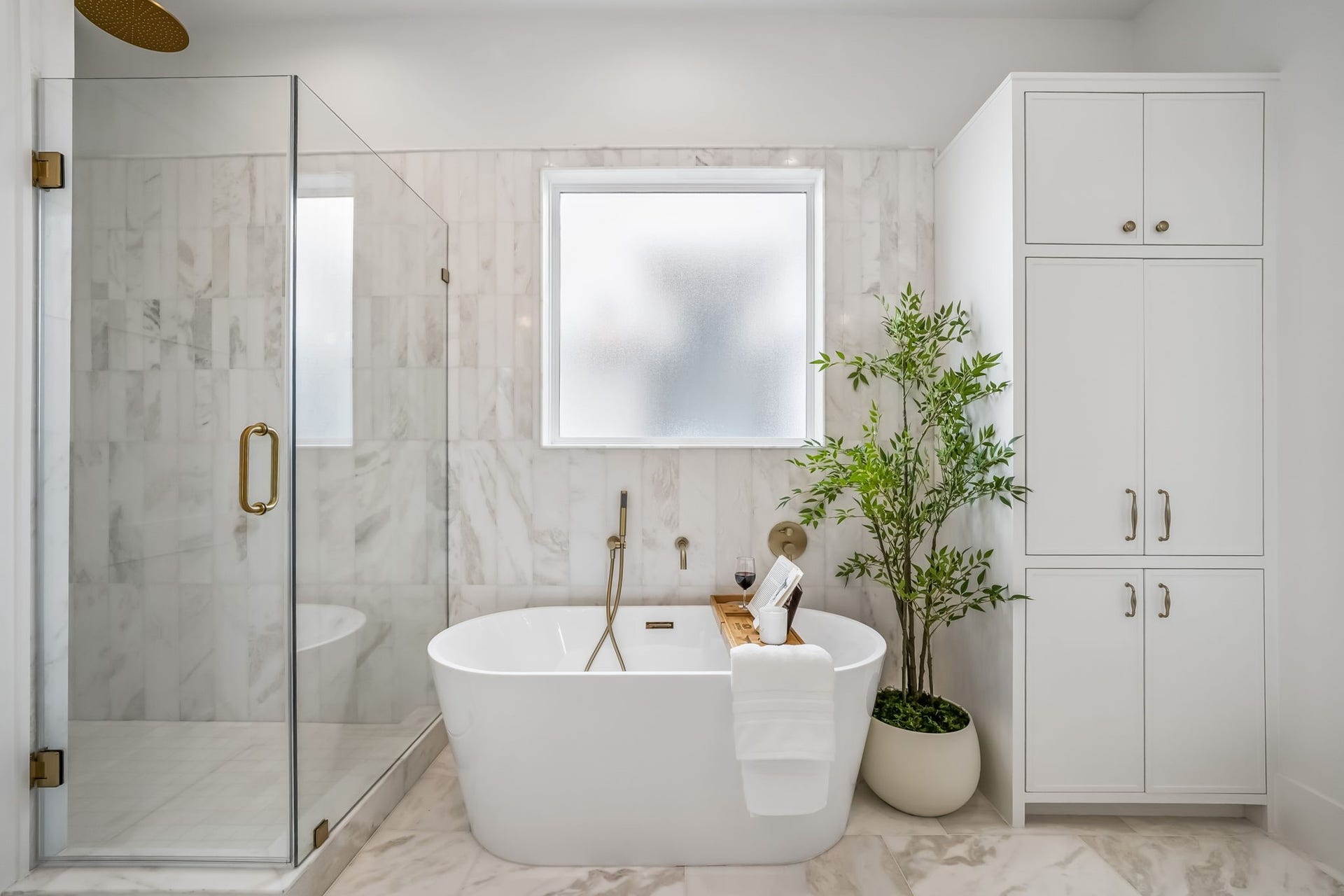 A custom linen cabinet provides beautifully integrated storage, while the soaking tub and spacious walk-in shower create a spa-like retreat. A frosted glass window allows natural light to pour in while maintaining privacy.