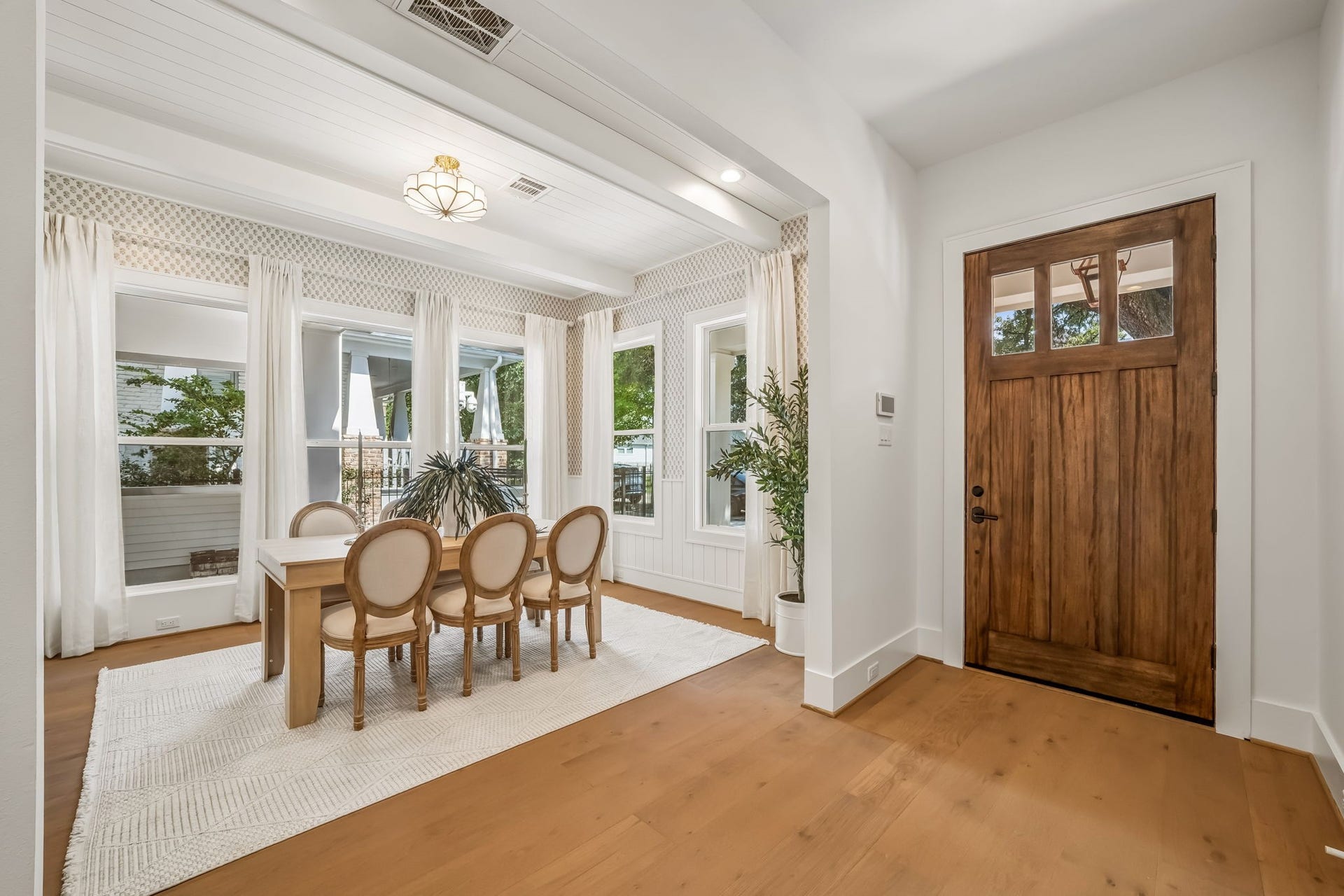 Step inside through the oversized front door, where an abundance of natural light immediately welcomes you into the home. The dining area makes a statement with Phillip Jeffries wallpaper, custom shiplap detailing, and panoramic views that create an elegant backdrop for every occasion.