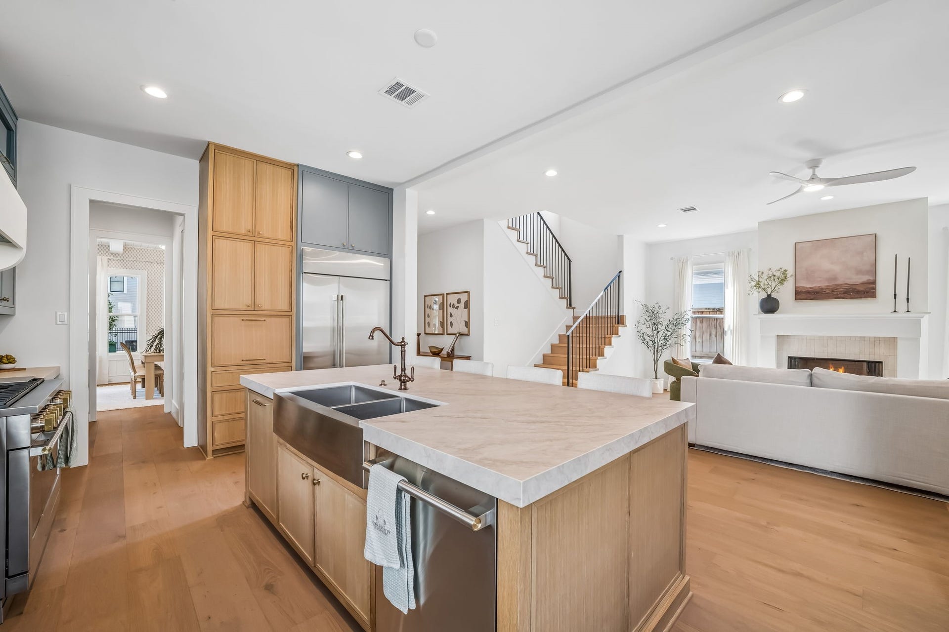 Spacious open-concept kitchen and living area featuring a large island, stainless steel appliances, warm wood cabinetry, and hardwood floors.