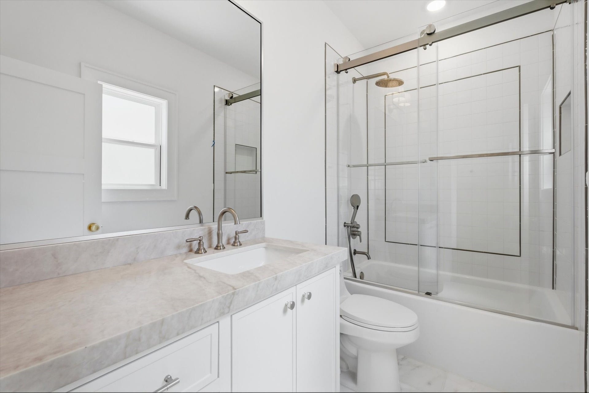 The apartments full bath carries the same elevated finishes found throughout the main residence, featuring Taj Mahal quartz, delicate tile detailing, and timeless marble flooring.