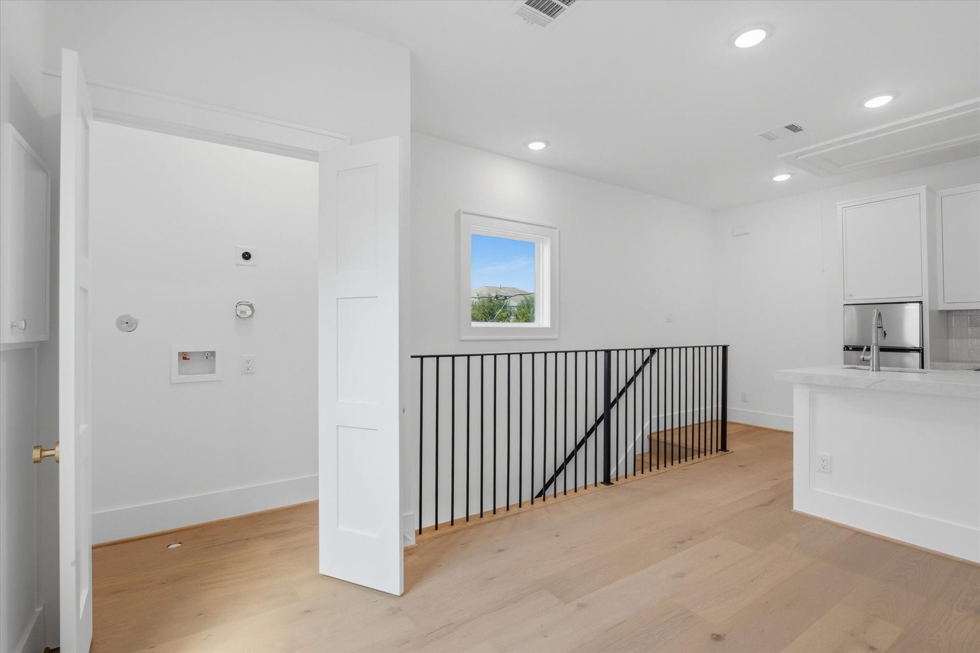 Hardwood flooring continues seamlessly into the garage apartment, maintaining the same elevated finish throughout. Pictured is the apartments dedicated laundry closet.