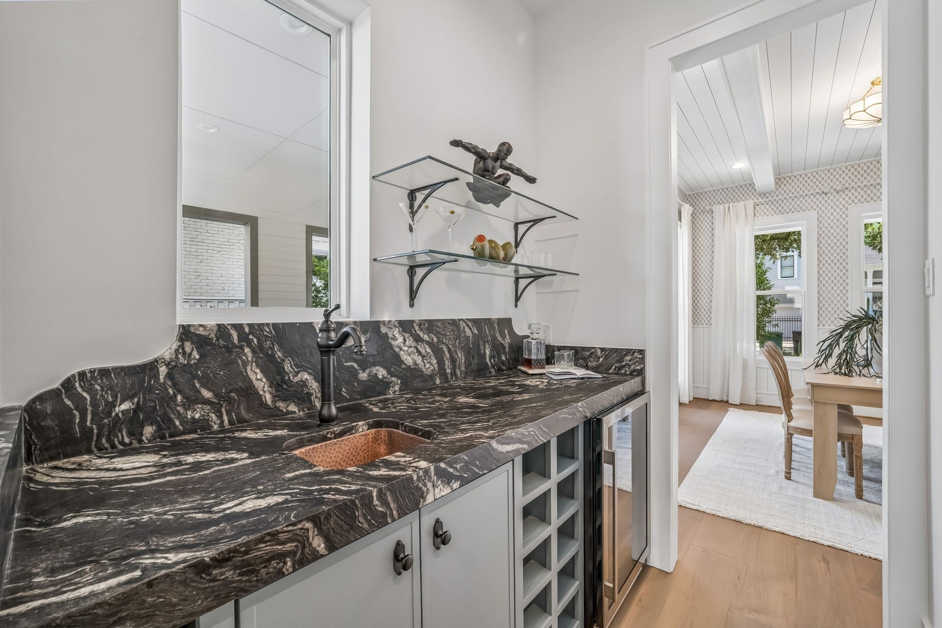 Conveniently positioned between the dining room and kitchen, the wet bar is designed for effortless entertaining. Complete with a beverage refrigerator, copper sink, and ample storage for wine and decorative glassware, every detail feels both functional and beautifully considered.