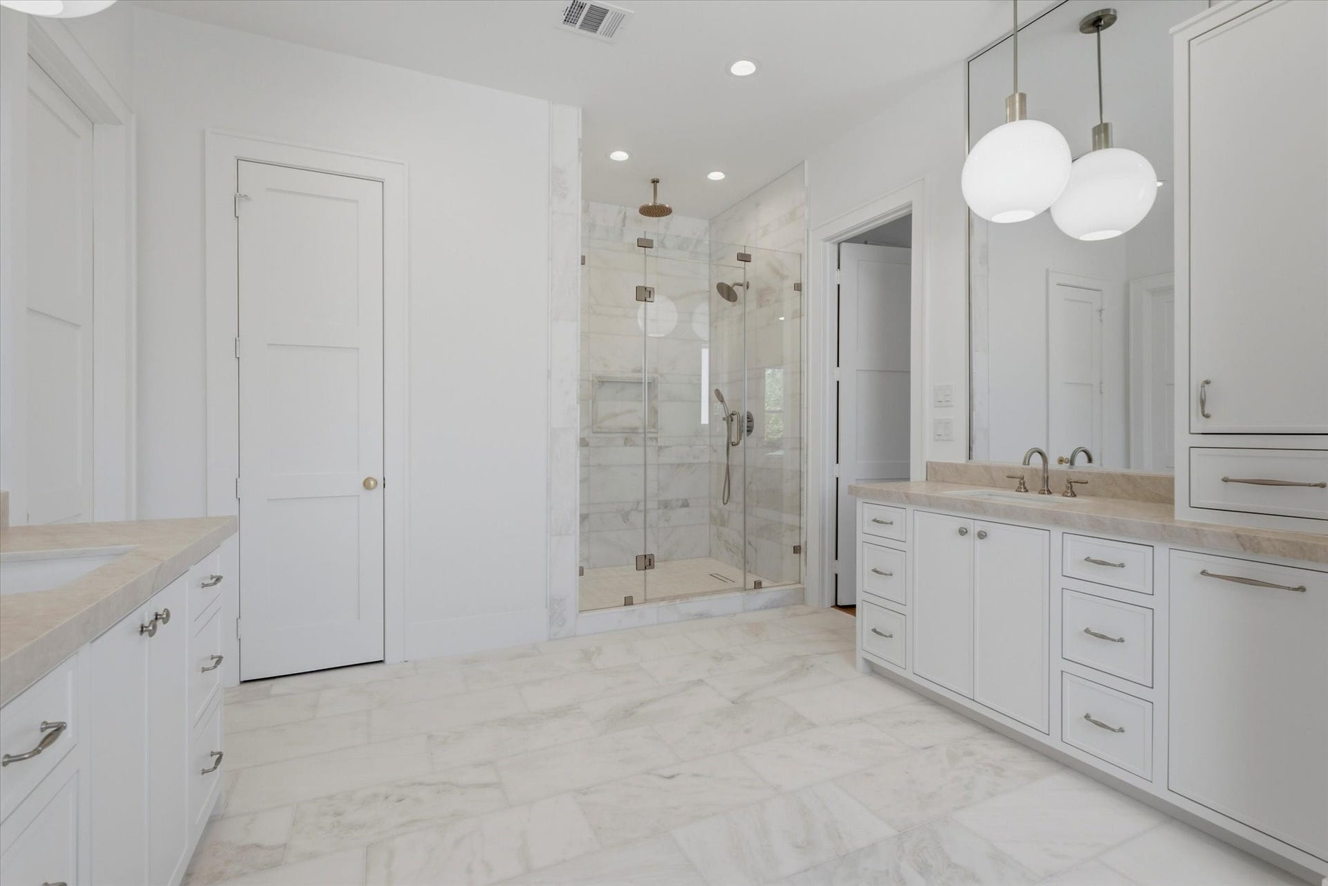 Separate vanities offer generous storage, complemented by an oversized walk-in shower.