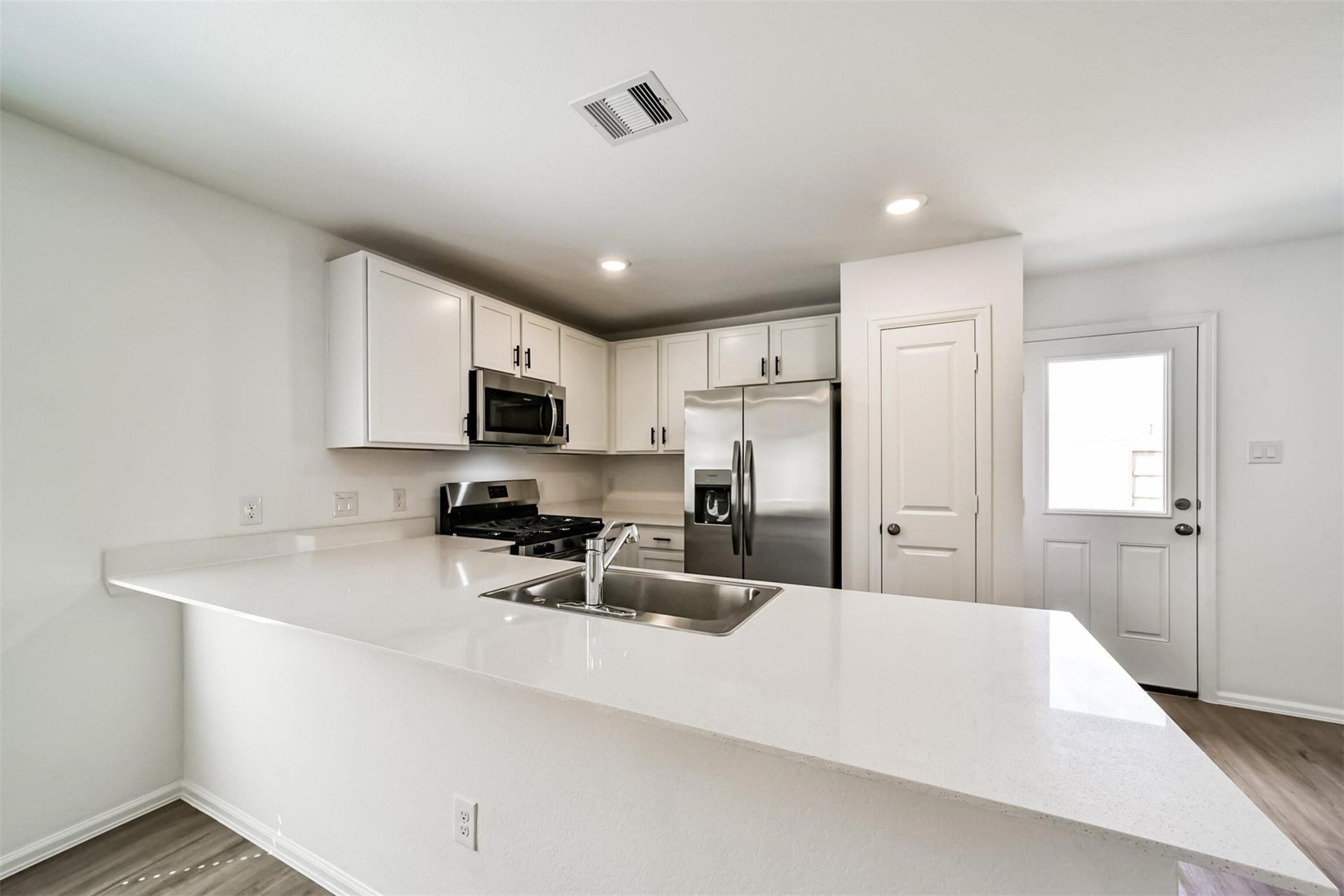 Beautiful kitchen featuring crisp white cabinets, black hardware, and stainless steel appliances.