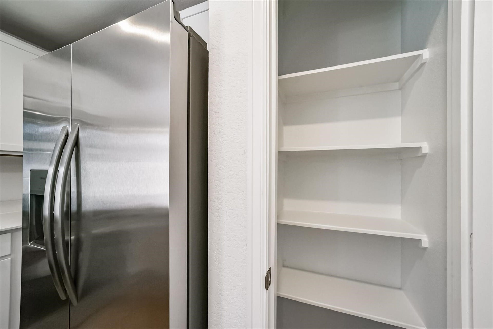 Convenient walk-in pantry offering ample shelving and storage space