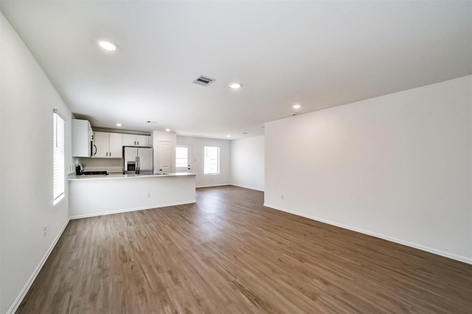 Beautiful open-concept living area connecting seamlessly to the kitchen on the left, featuring a large breakfast bar island with plenty of space for everyday living and entertaining
