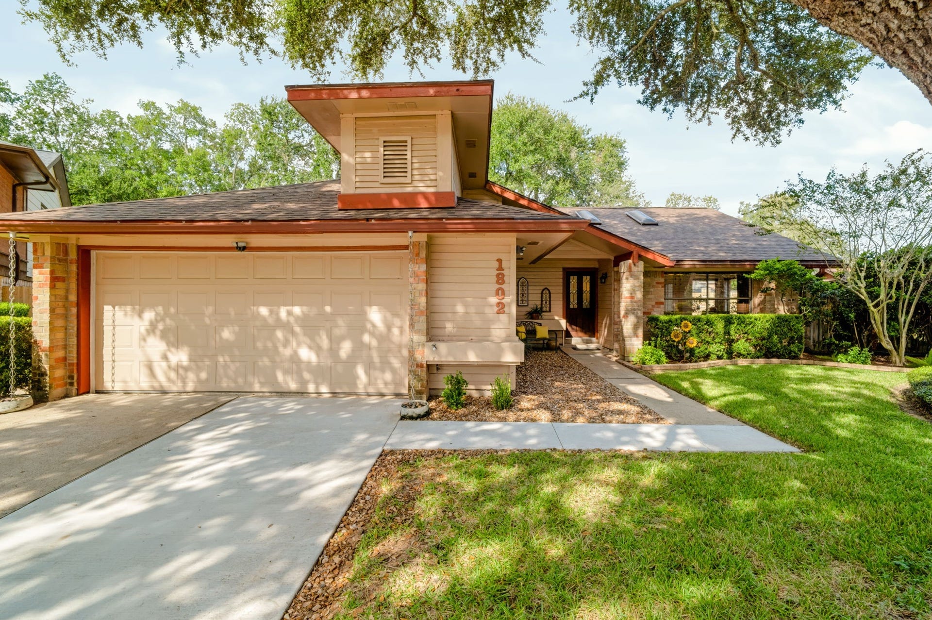 1802 Brushy Creek Drive, Sugar Land, TX 77478 A spacious double-wide driveway leads to the attached two-car garage, offering ample parking. Inside, storage racks provide additional organization, while the floored attic above offers even more storage space.